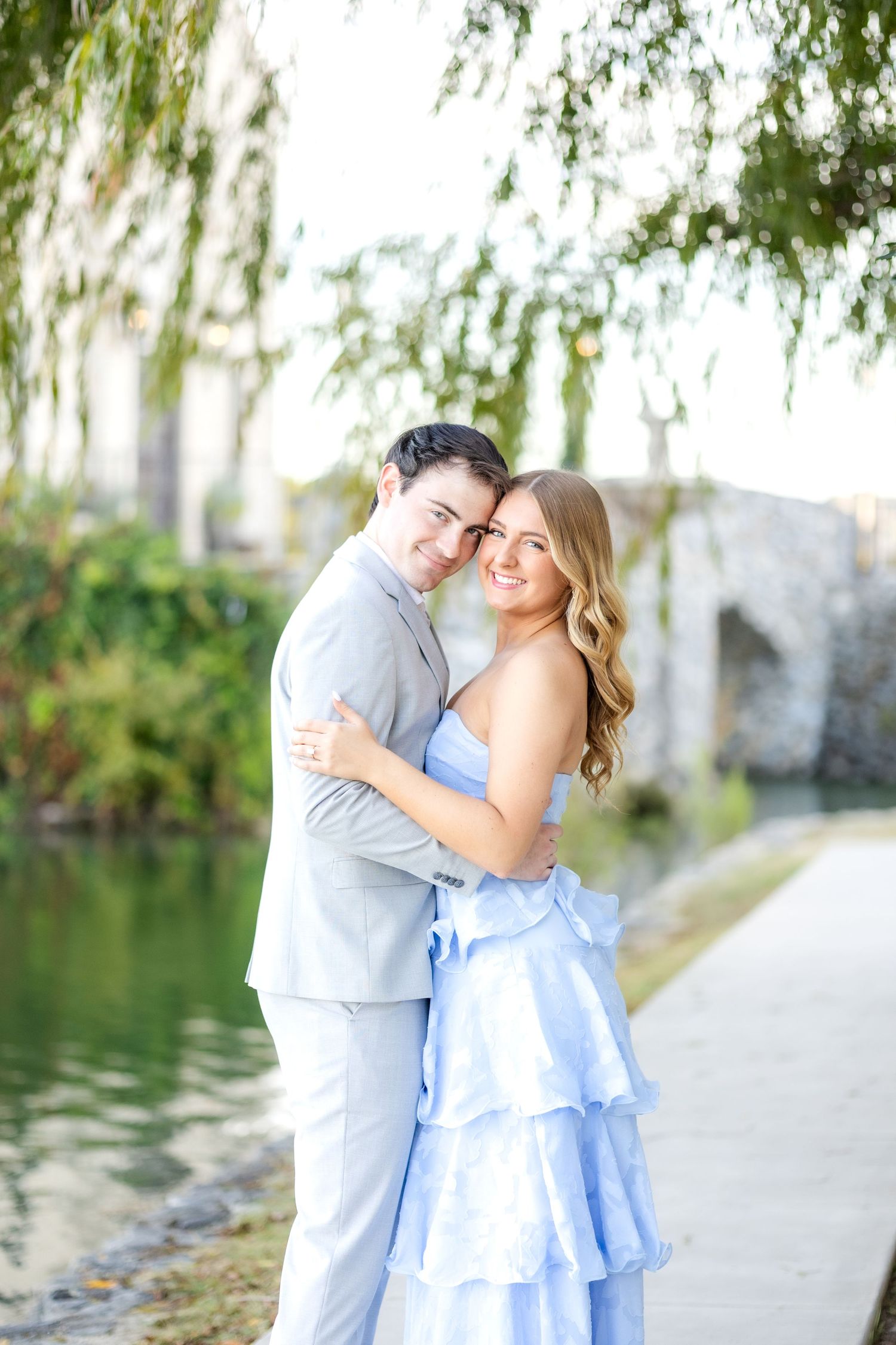 Dallas engaged couple hugging each other and smiling really big under a tree at Adriatica Village engagement session in McKinney, TX