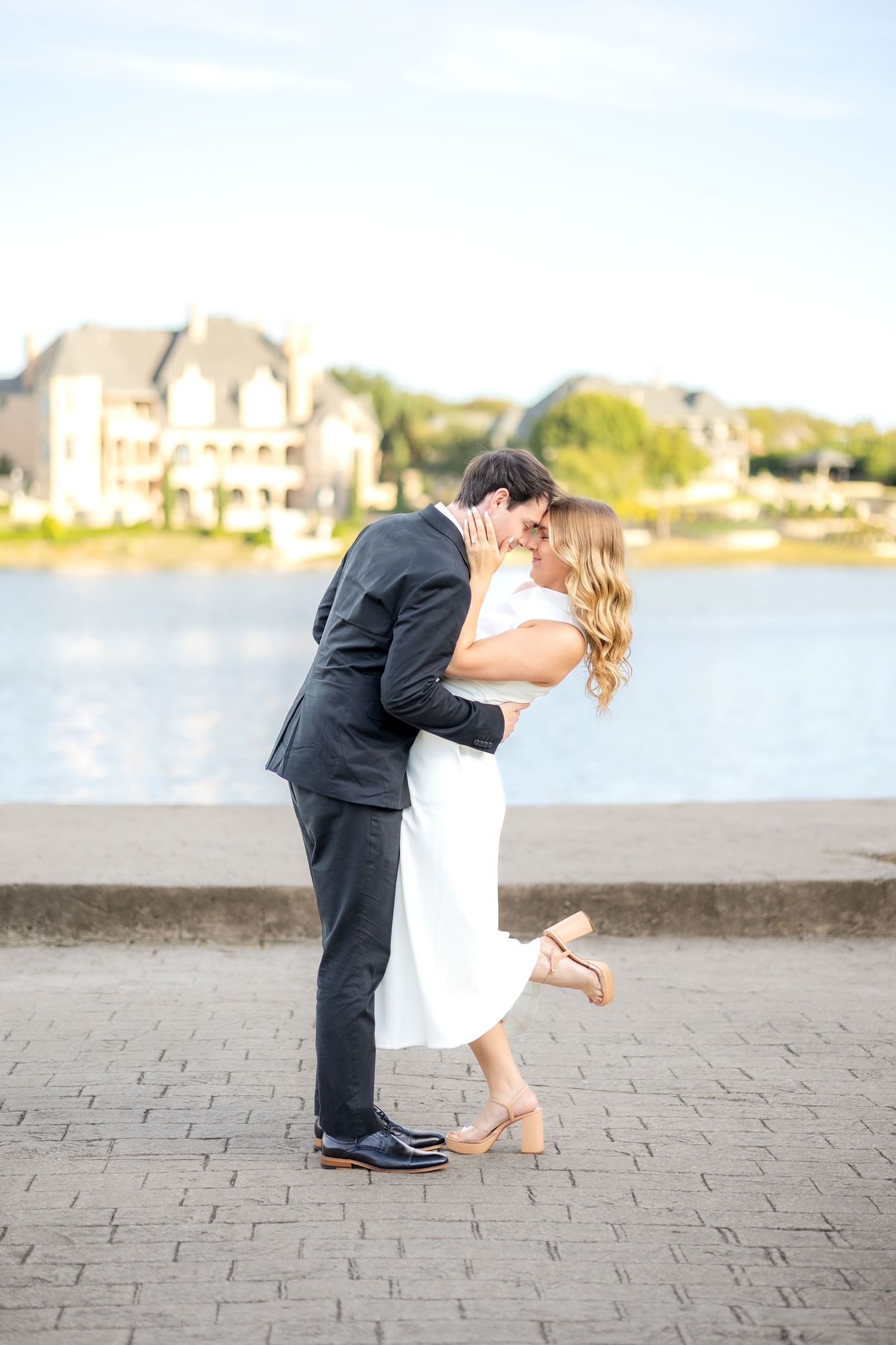 Engaged couple doing a romantic dip and resting heads together on the dock overlooking a beautiful lake at Adriatica Village engagement