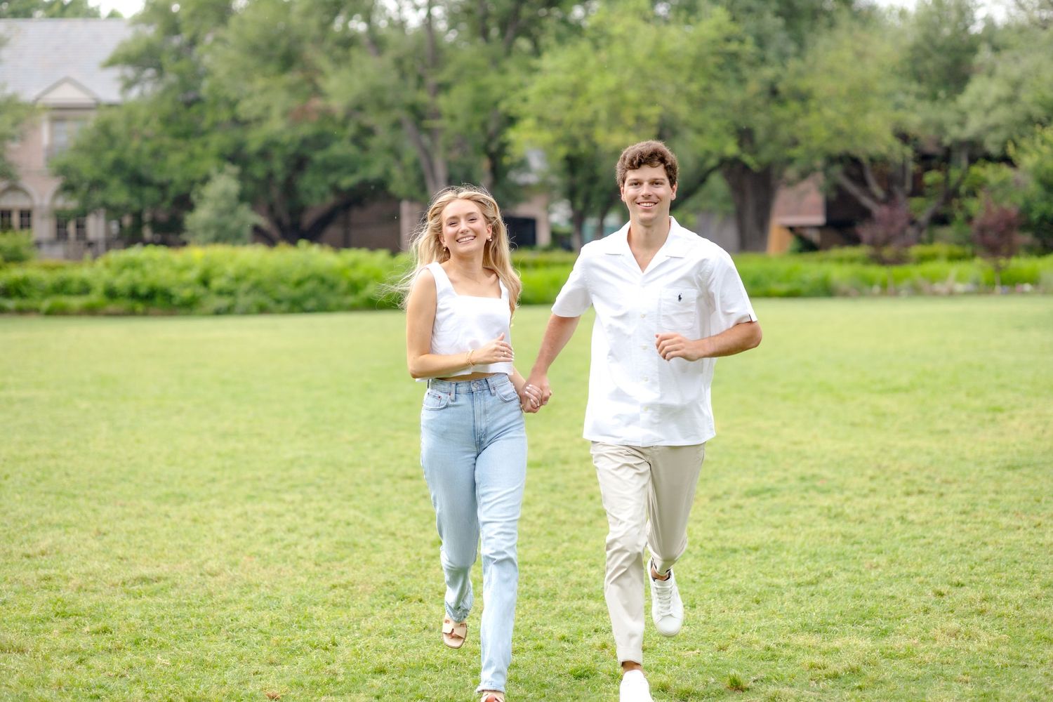 Engaged couple laughing and running with one another at Flippen Park during their engagement photo session in Dallas