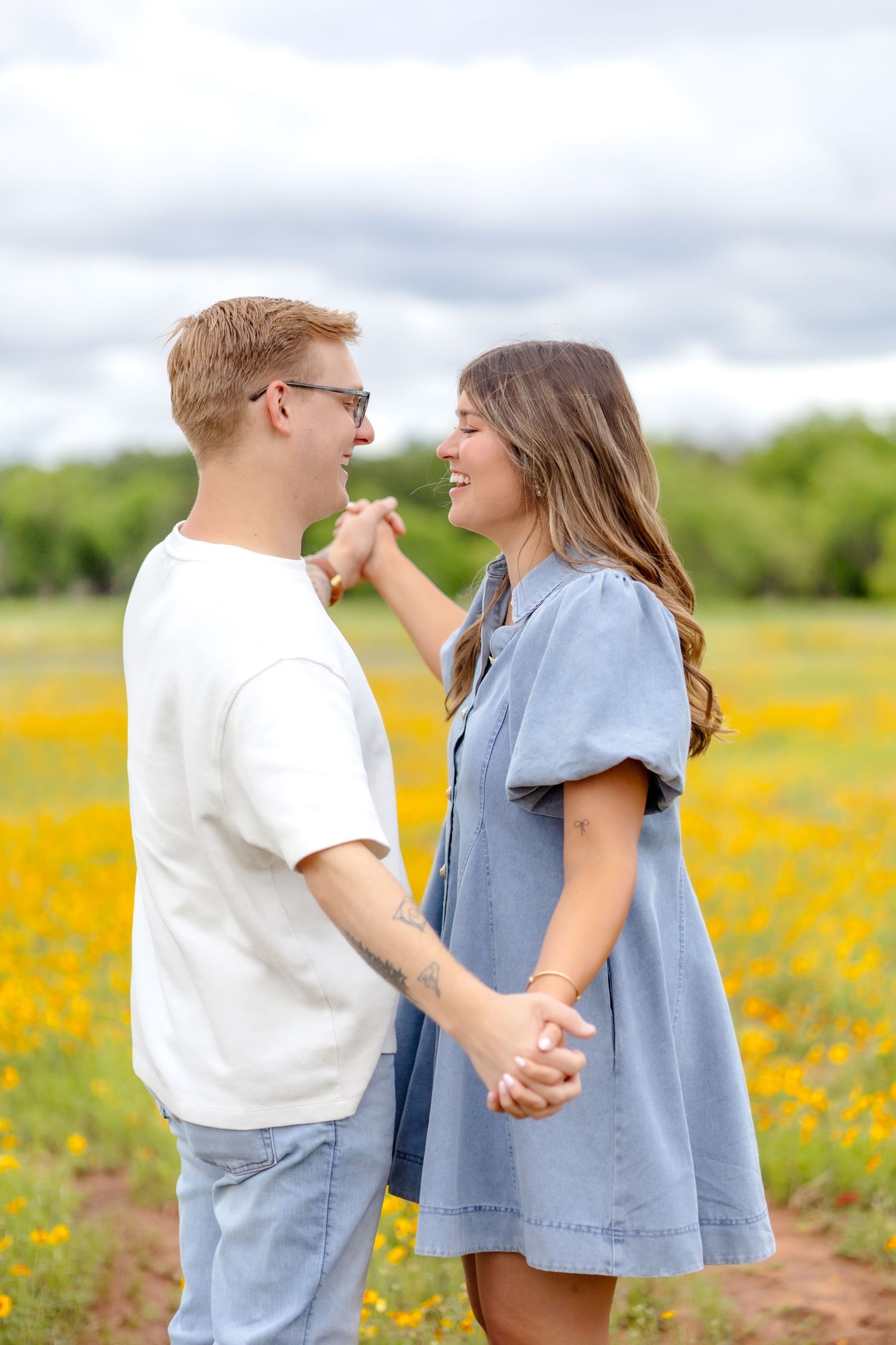 husband and wife holding hands and laughing together in a field of yellow flowers in Abilene, Texas