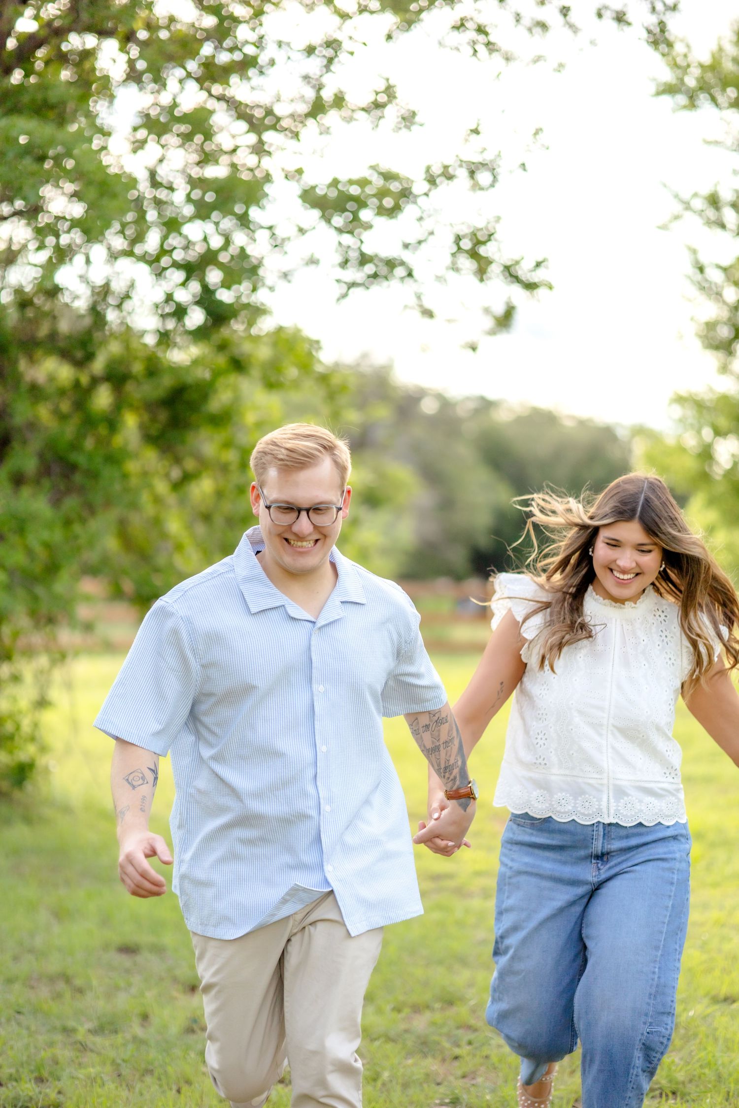 Husband and wife holding hands and running as fast as they can through a field at golden hour in Abilene, TX