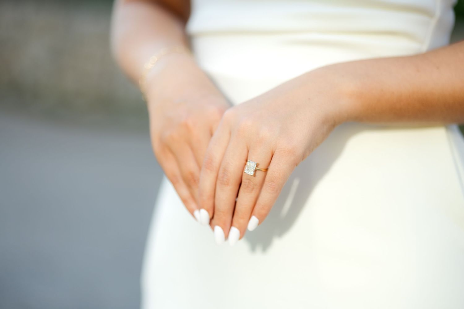 Bride holding her hands in front of her, showing off her shiny engagement ring at Dallas engagement session