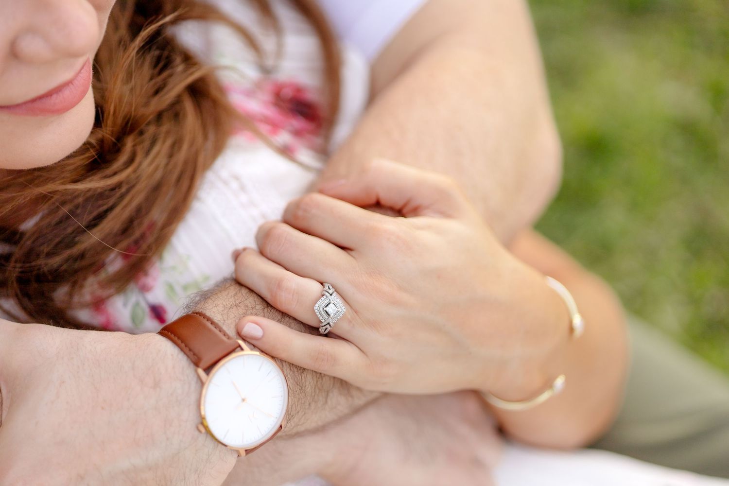Detail image of engaged couple sitting and hugging, showing off the engagement ring at White Rock Lake in Dallas, Texas