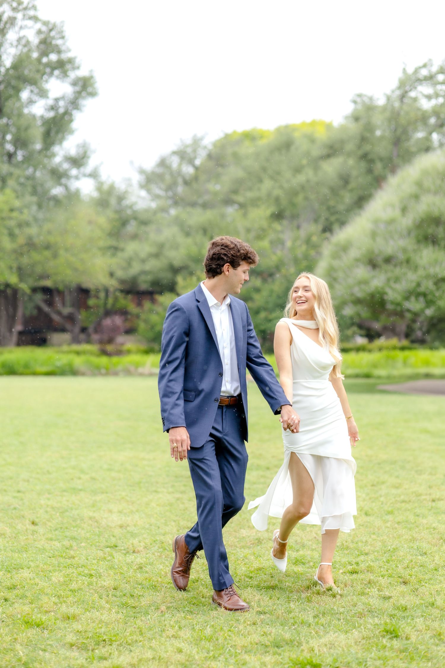 Luxury engagement session with a couple walking hand-in-hand through a field in Dallas, Texas