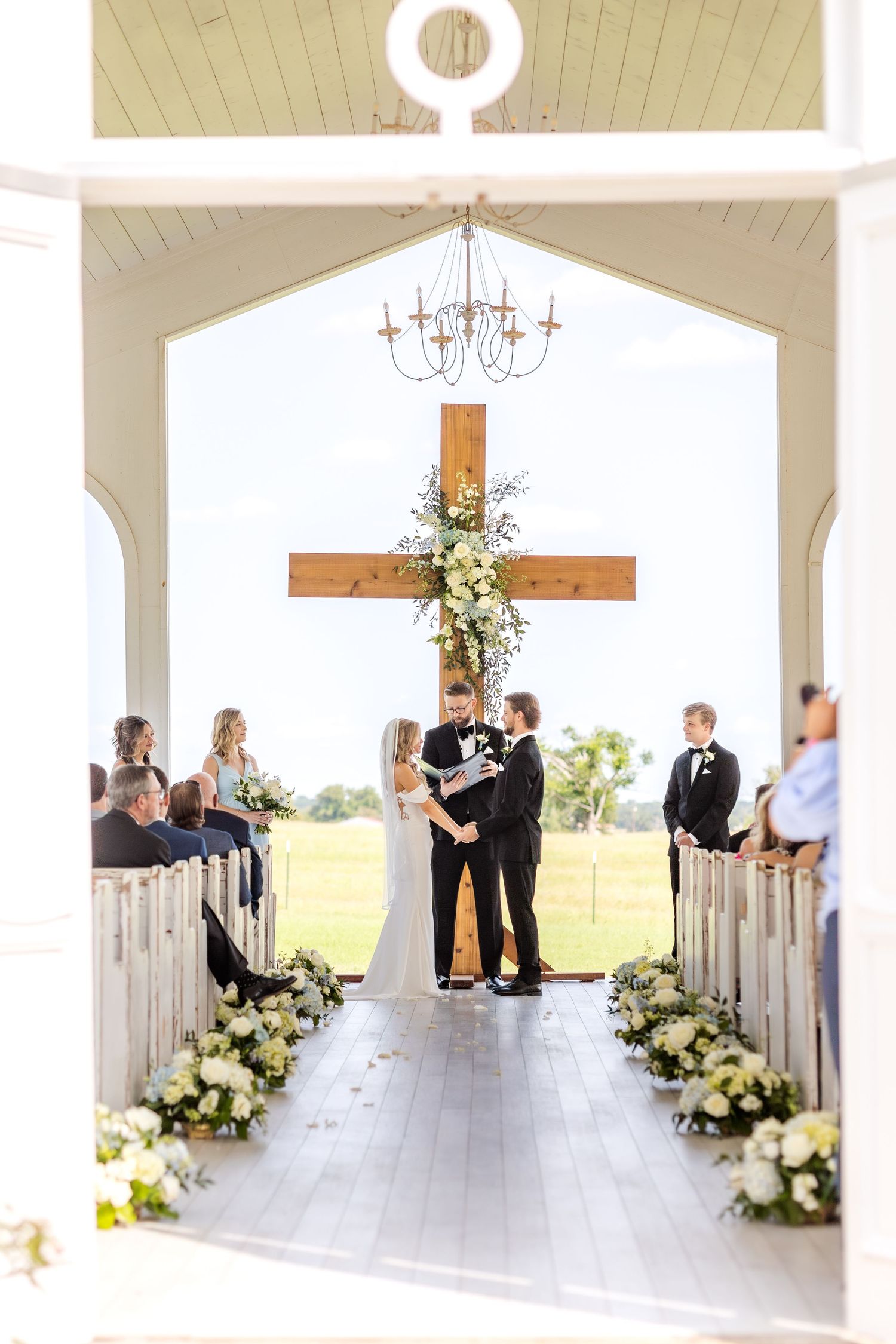 Dallas wedding ceremony at Chandelier Farms with bride and groom holding hands at the altar in front of a cross