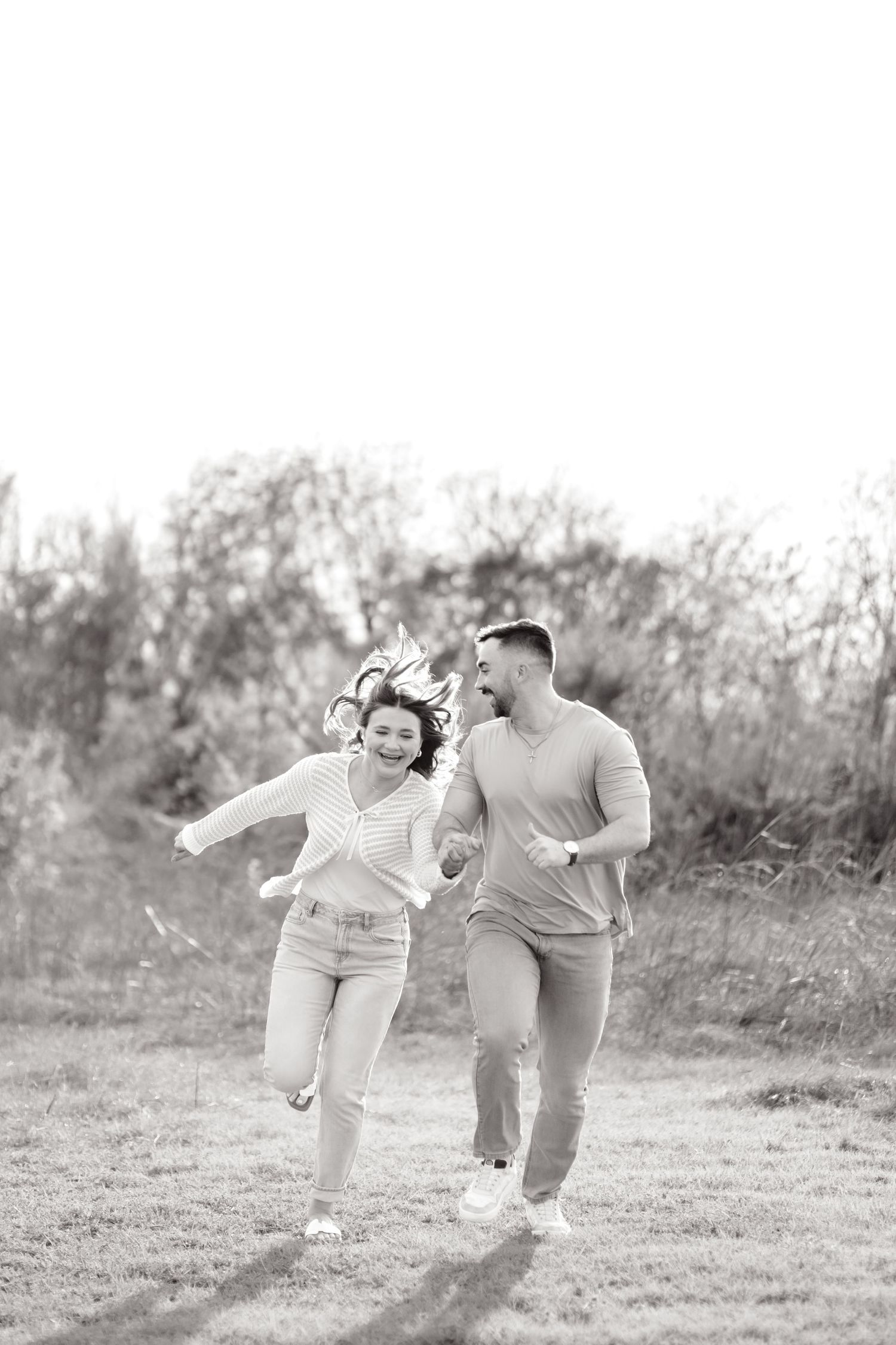couple running fast through a field at White Rock Lake