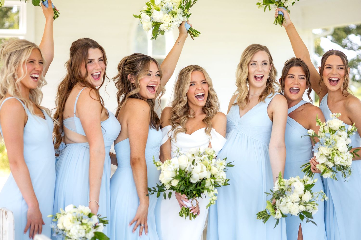 Bride and bridesmaids holding their bouquets up and down in excitement