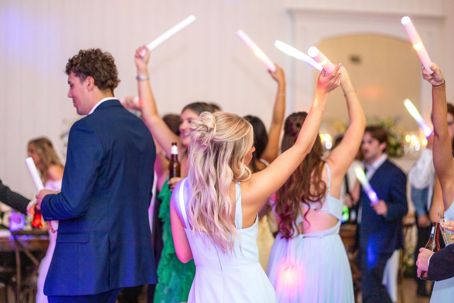 Spring wedding guests dancing at wedding reception in Dallas, Texas with glow sticks waving in the air