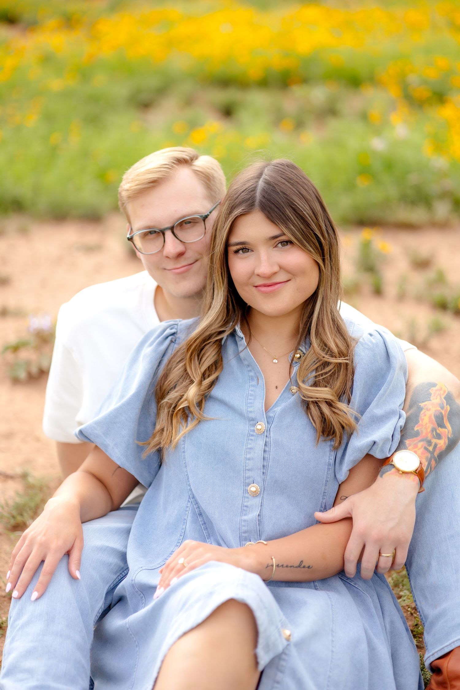Married couple sitting together in a field and soft smiling during couple's photo session