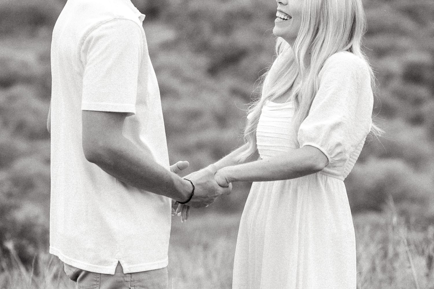 Black and white image of engaged couple holding hands and smiling