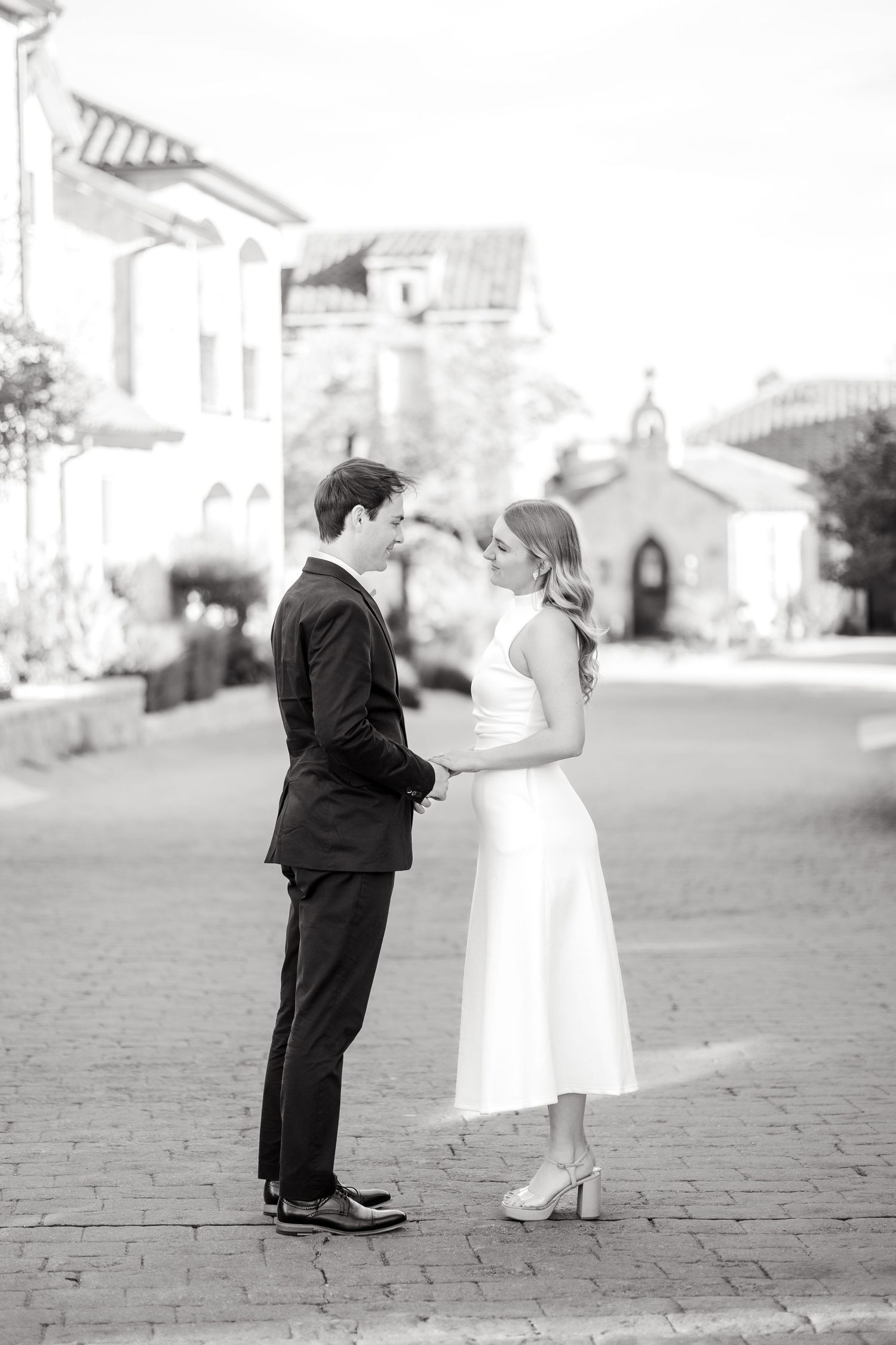Engaged couple standing and holding hands sharing what they love about one another during engagement session at Adriatica Village