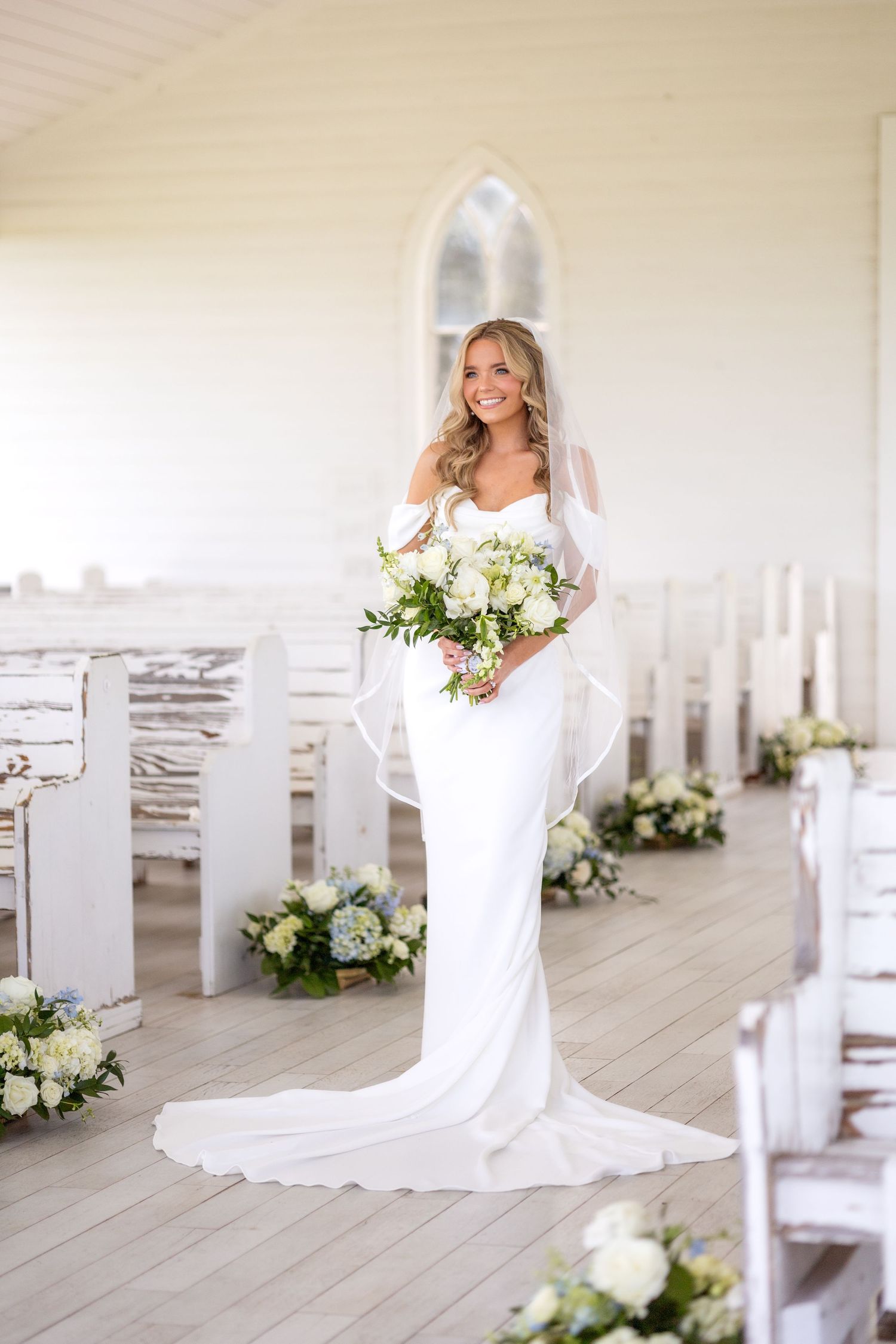 Bride smiling and holding spring wedding flowers at Dallas wedding chapel