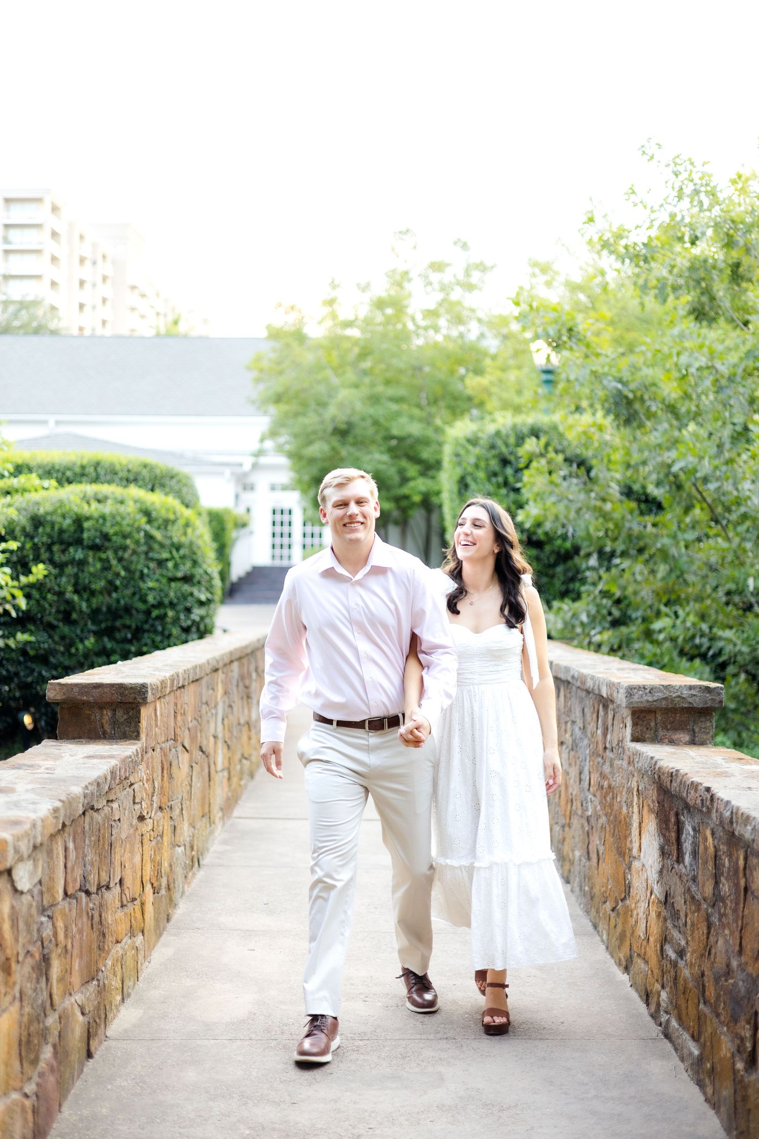Engaged couple walking on a bridge while holding hands and laughing together
