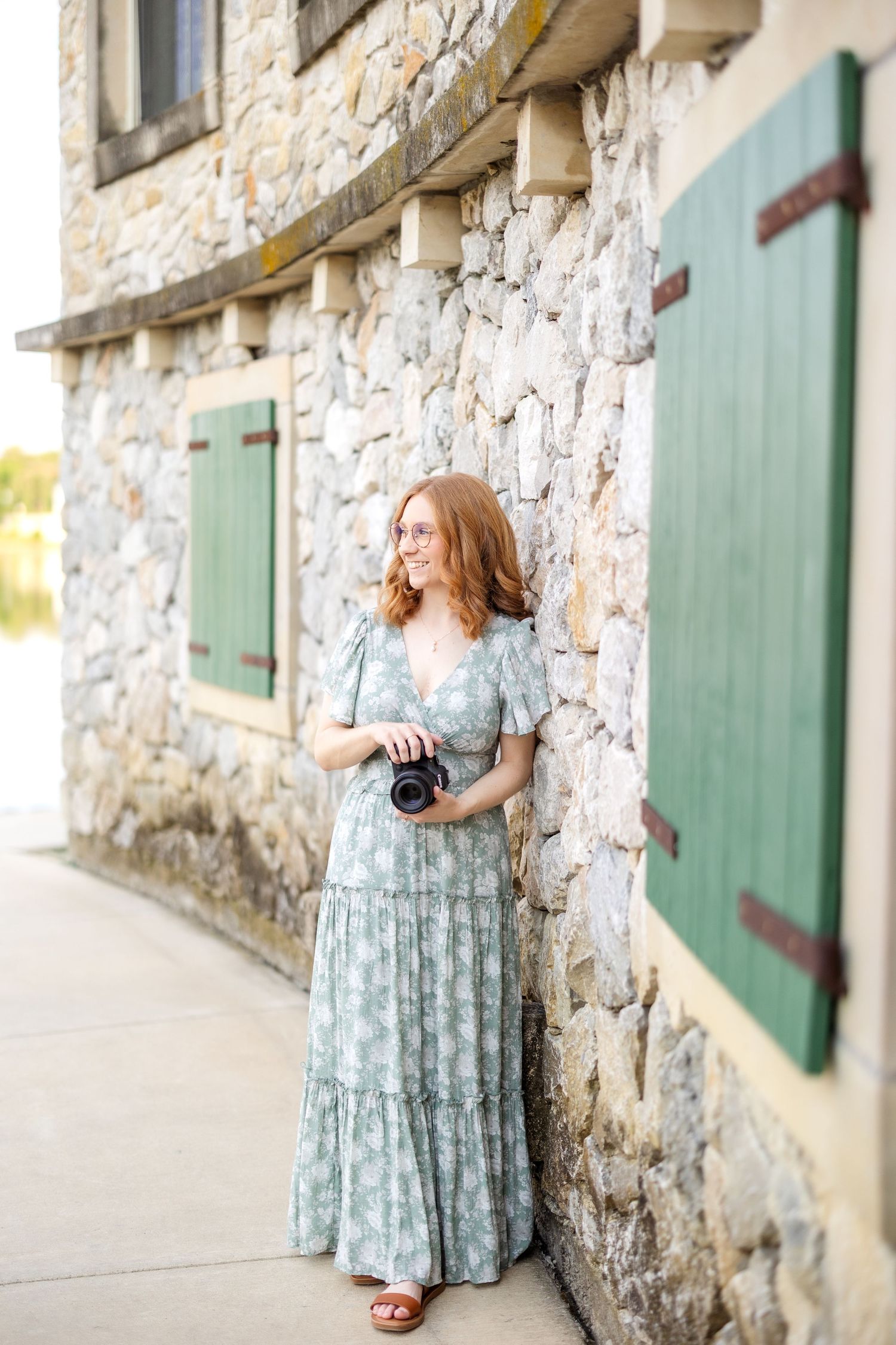 Wedding photographer smiling off to the side at Adriatica Village while leaning on a wall