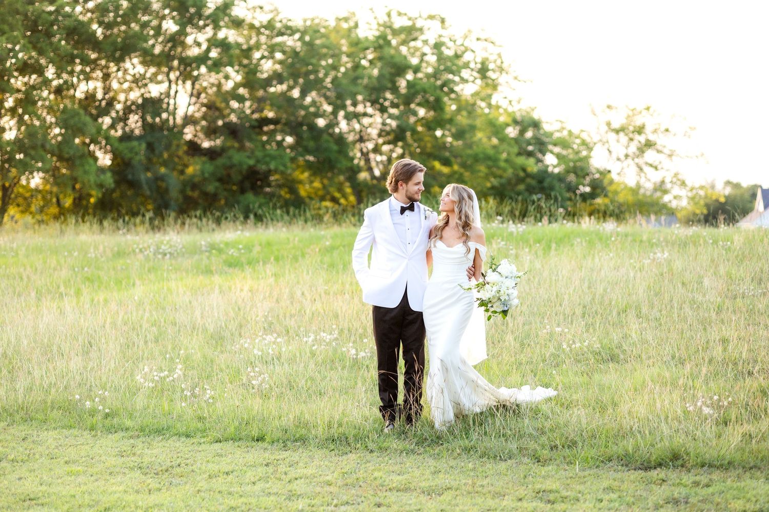 Bride and groom walking in a field at Chandelier Farms during sunset on beautiful Spring wedding day