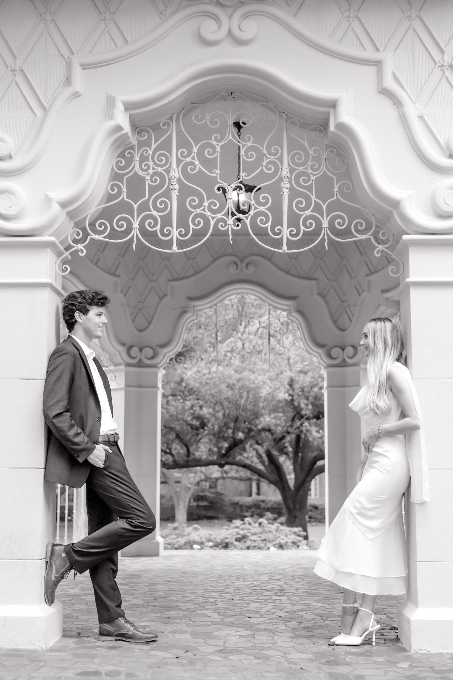 Engaged couple leaning against the walls of the gazebo at Flippen Park and smiling at one another during Dallas engagement photo session