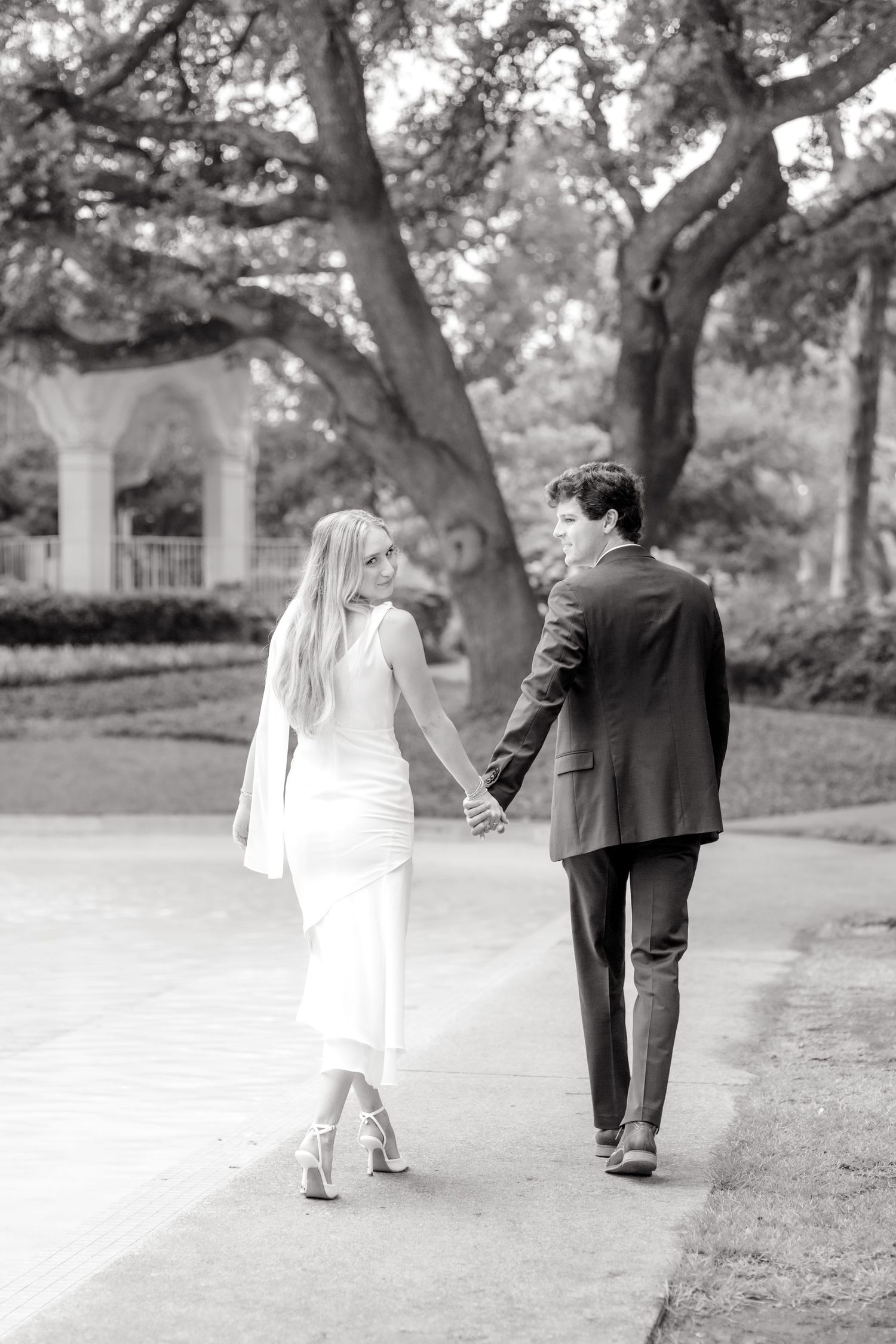 Black and white image of engaged couple walking away at luxury engagement photo session at Flippen Park in Dallas, TX