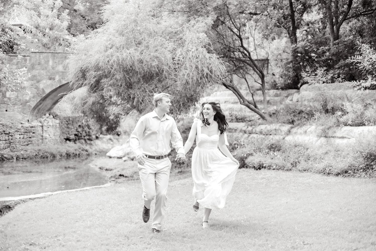Engaged couple running together by a pond and laughing