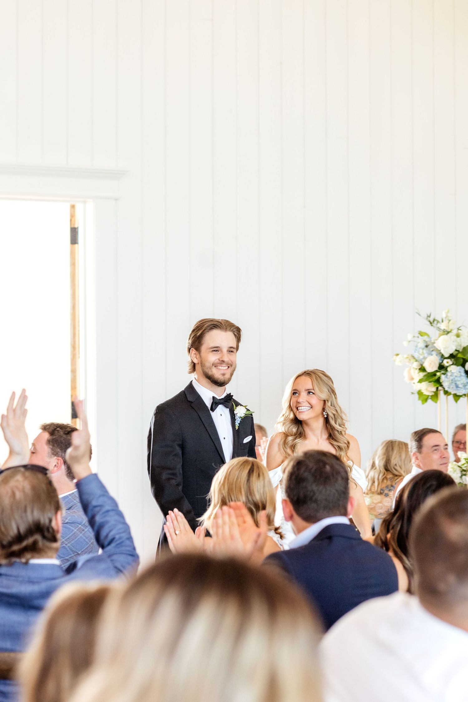 Bride and groom entering their Dallas wedding reception as guests clap and cheer