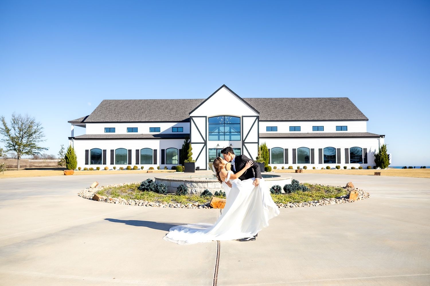 Bride and groom dip kiss in front of The Gardenia Venue wedding