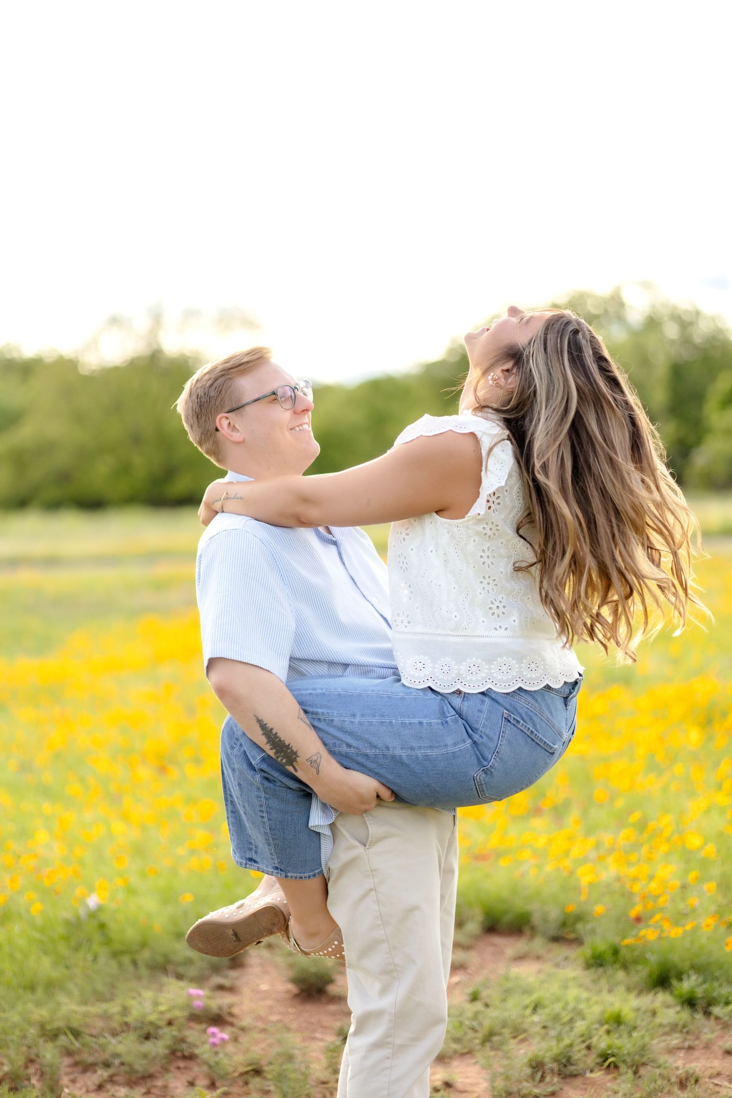 Husband and wife in a koala bind and he spins her around in the wildflower field in Abilene, TX