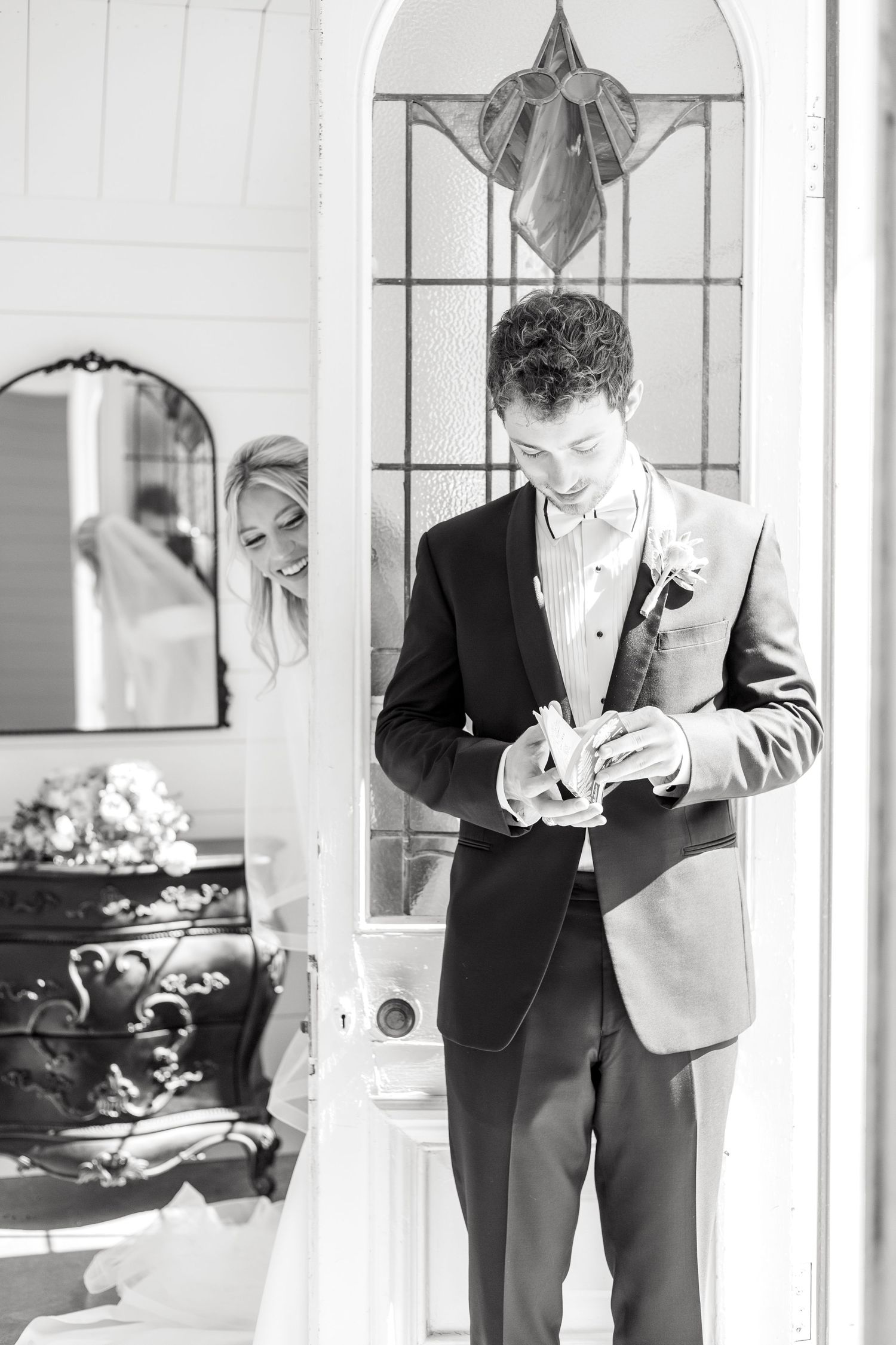Black and white image of a bride and groom sharing their first touch and the groom reading notes from the bride at Dallas wedding