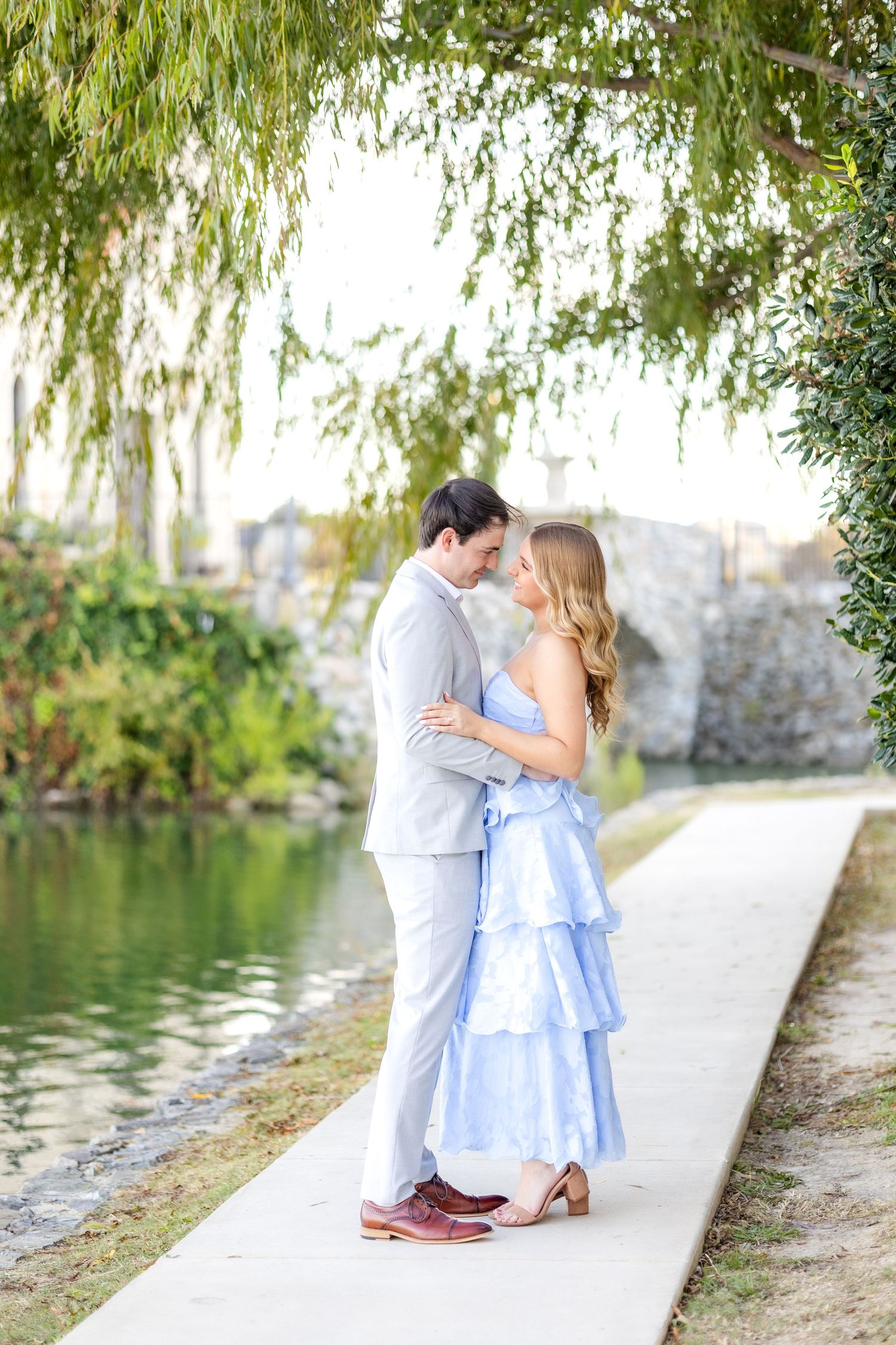 Engaged couple hugging one another and resting their foreheads together under a tree at Adriatica Village in McKinney, TX engagement session
