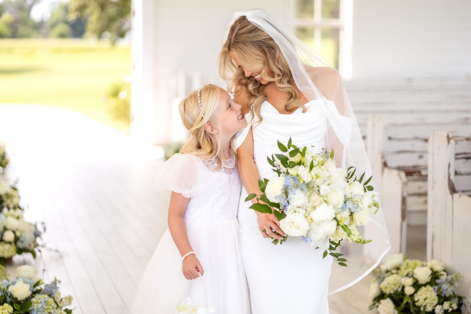 Bride and flower girl smiling at one another on Spring wedding day at Chandelier Farms