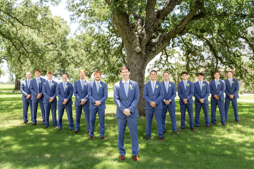 Groom and groomsmen in sharp blue suits standing outside at a classic summer wedding in Dallas