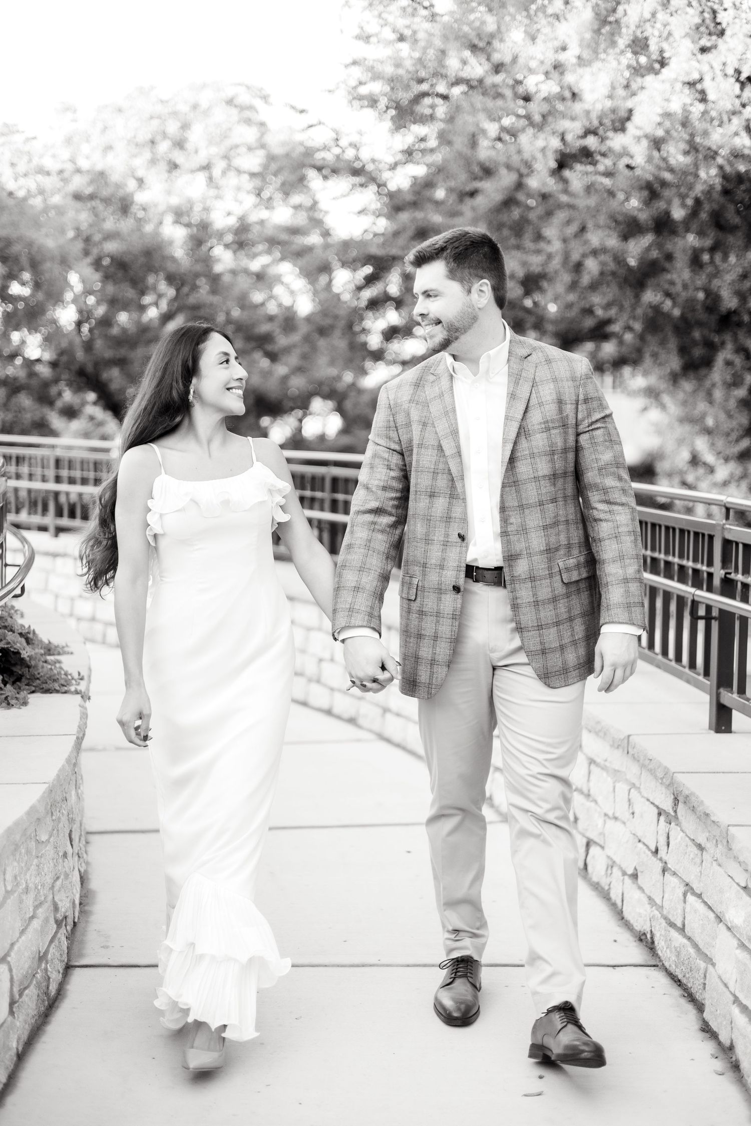 Engaged couple walking down a stone pathway while holding hands at Lakeside Park in Dallas, Texas during engagement photo session