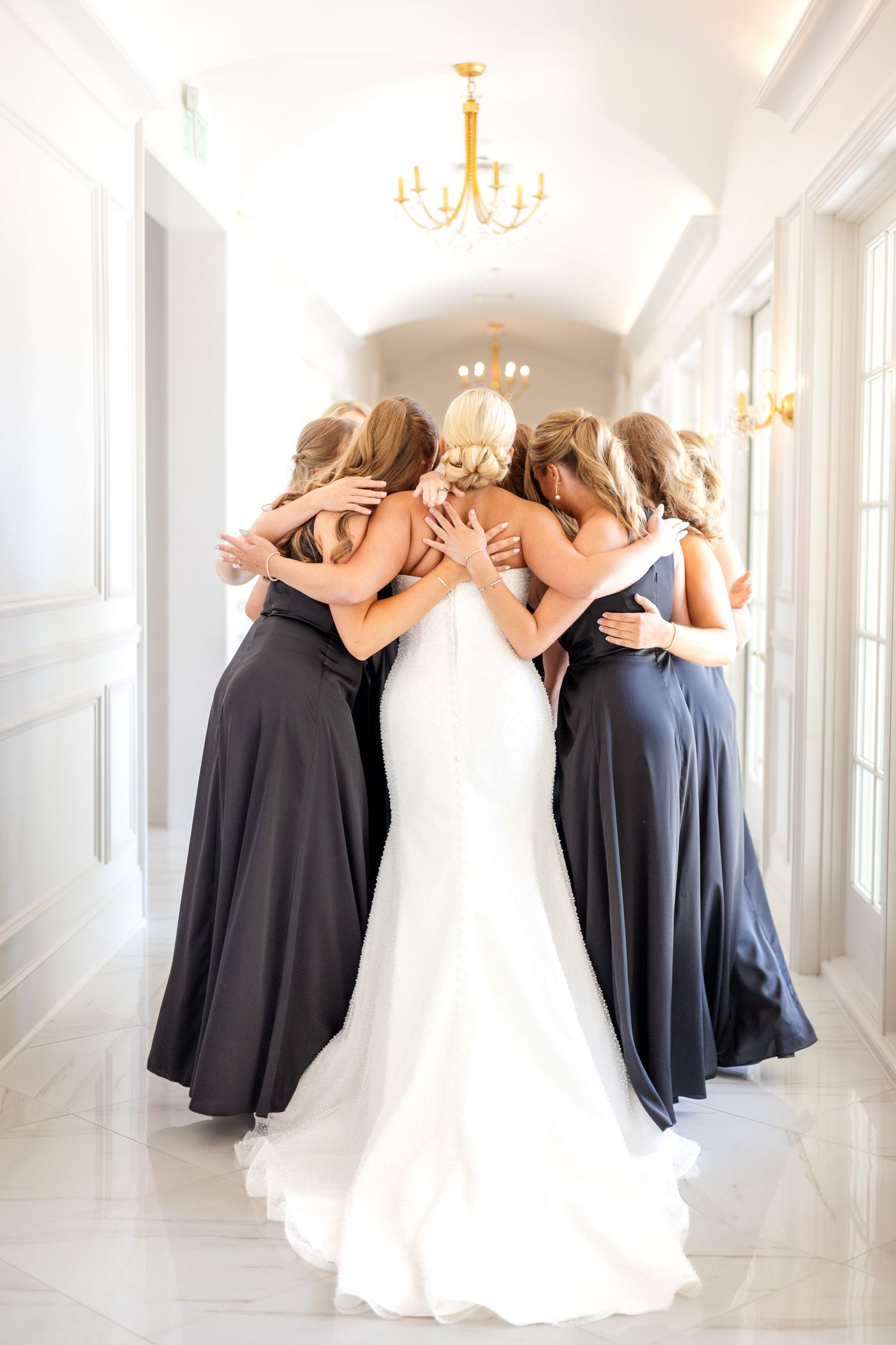 Bride and bridesmaids sharing a hug at luxury Dallas wedding venue in the summer