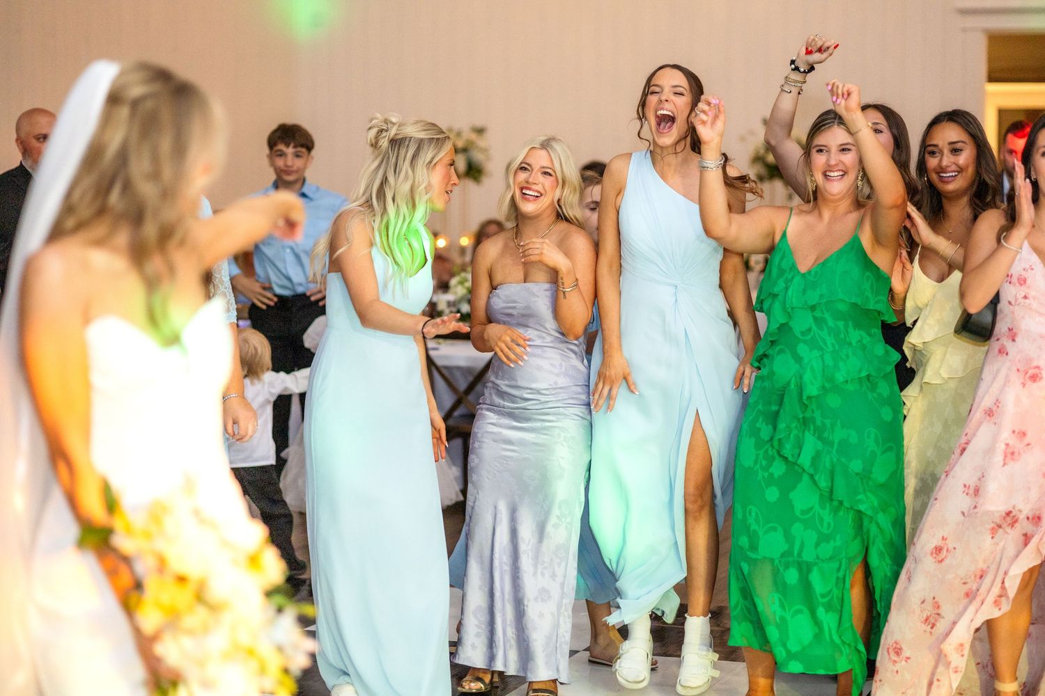 Female wedding guests dancing and getting excited just before the bride tosses her bouquet