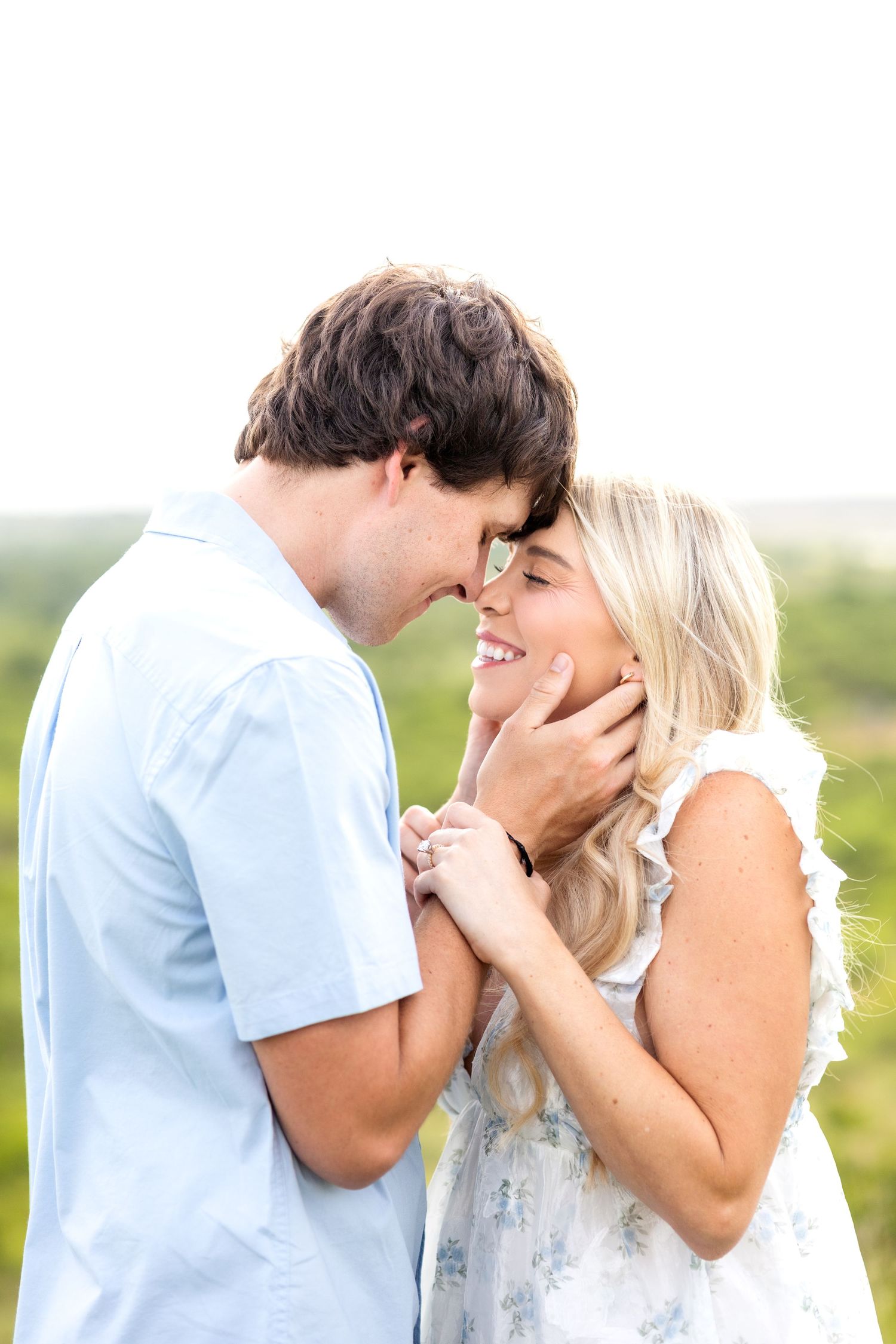 Engaged couple resting foreheads together while closing their eyes and smiling gently