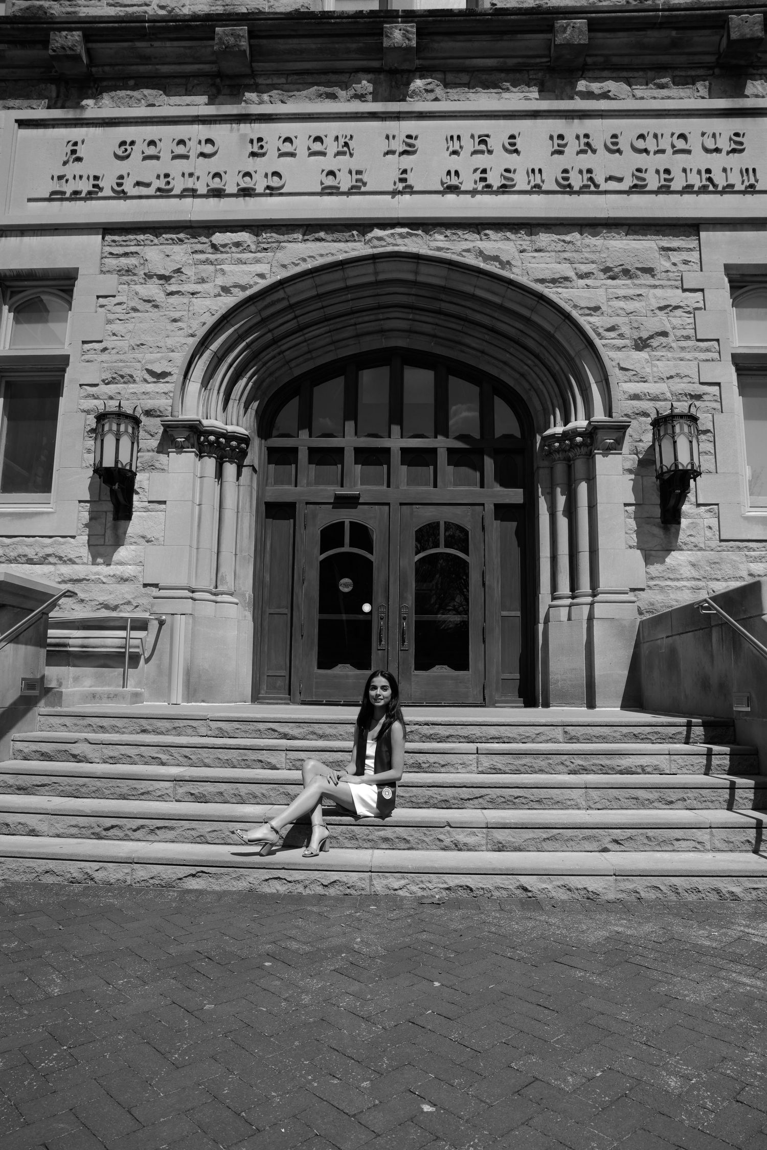 Picture of a girl sitting on stairs in front of the building she went to school in at IU campus