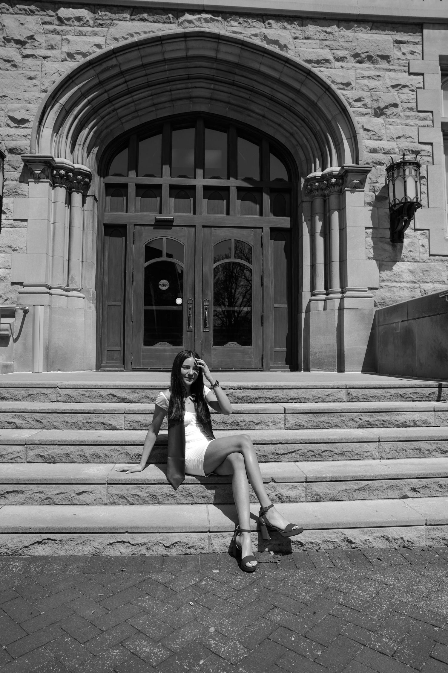 Picture of a girl sitting on stairs in front of the building she went to school in at IU campus