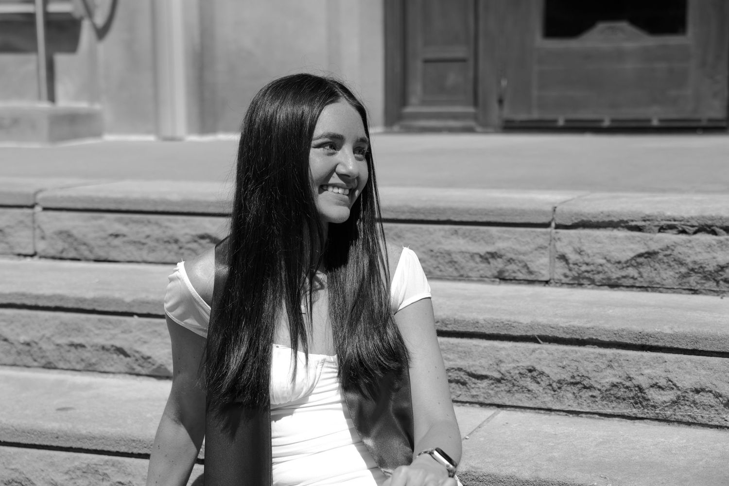 Picture of a girl sitting on stairs in front of the building she went to school in at IU campus