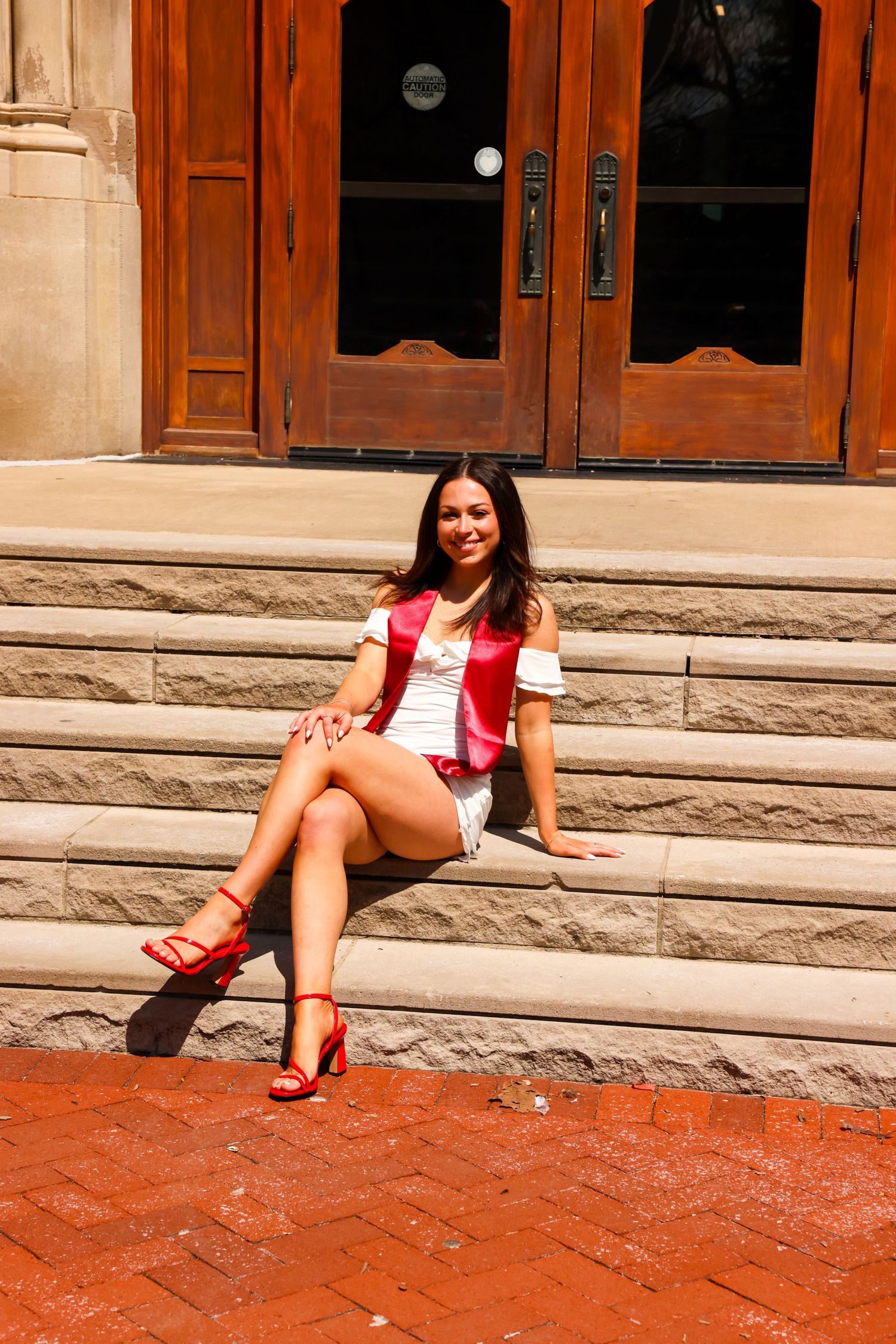 Picture of a girl sitting on stairs in front of the building she went to school in at IU campus