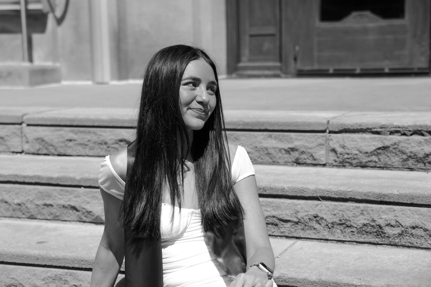 Picture of a girl sitting on stairs in front of the building she went to school in at IU campus