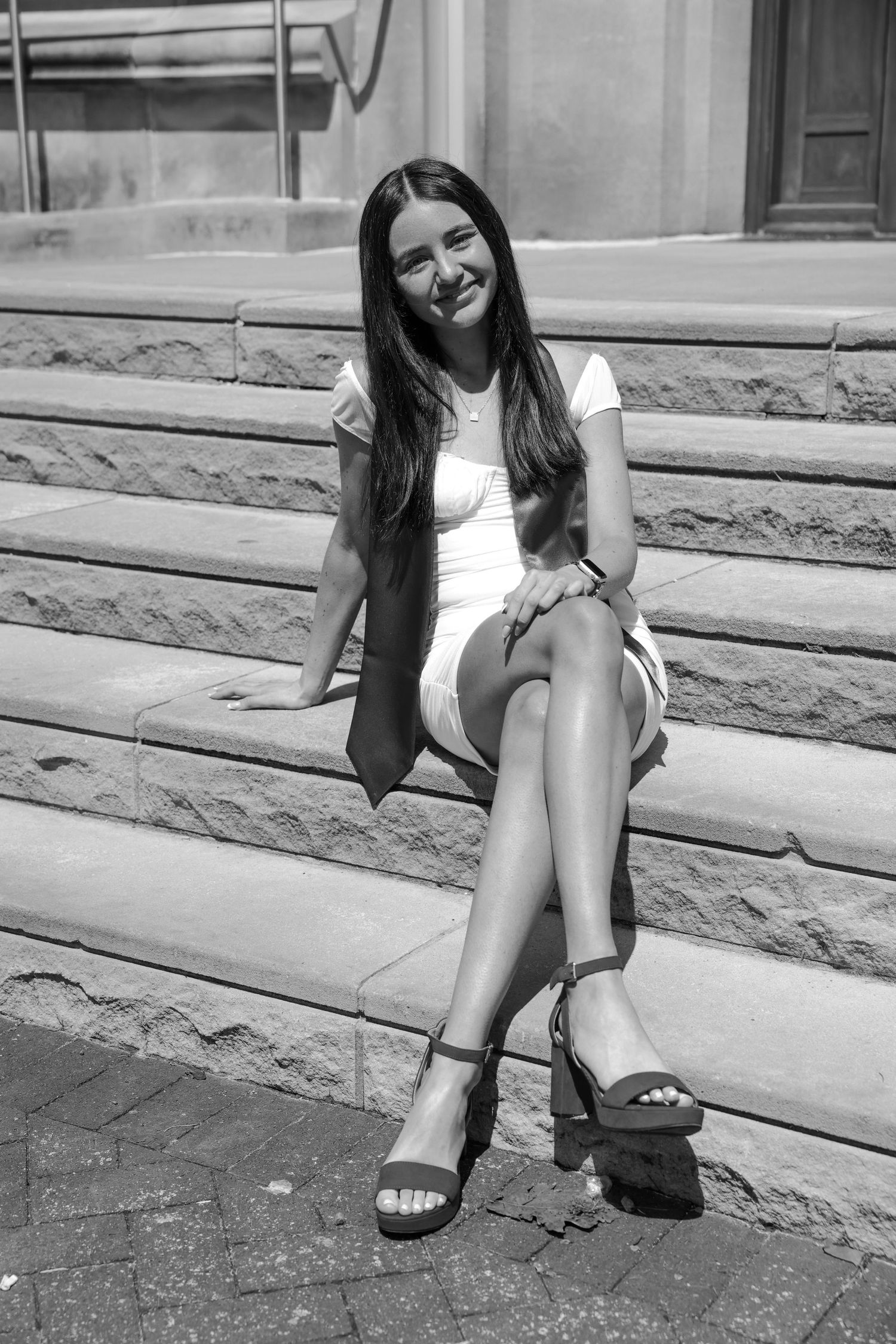 Picture of a girl sitting on stairs in front of the building she went to school in at IU campus