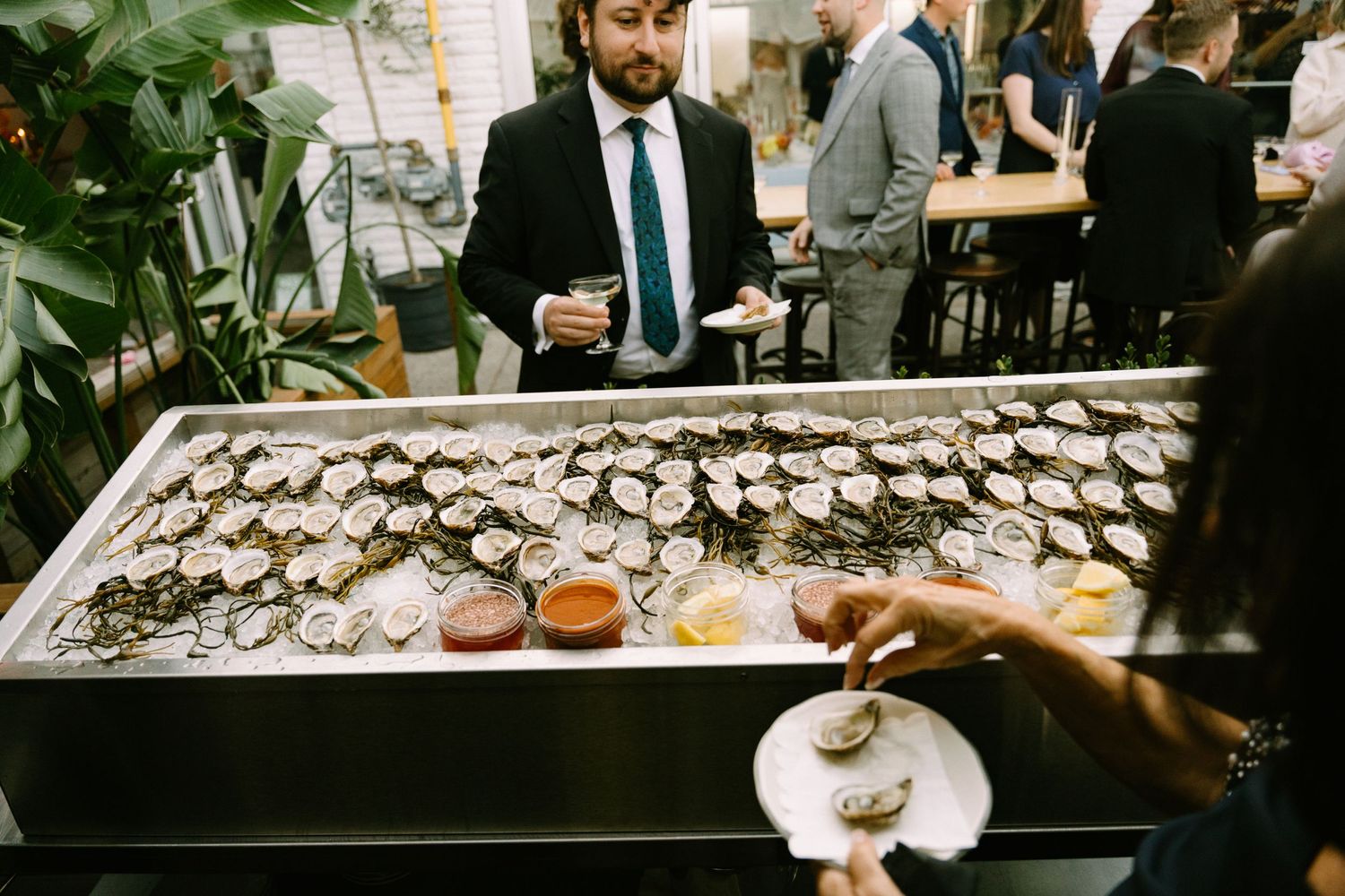 A large display of fresh raw oysters on ice at an upscale restaurant bar being served to guests.