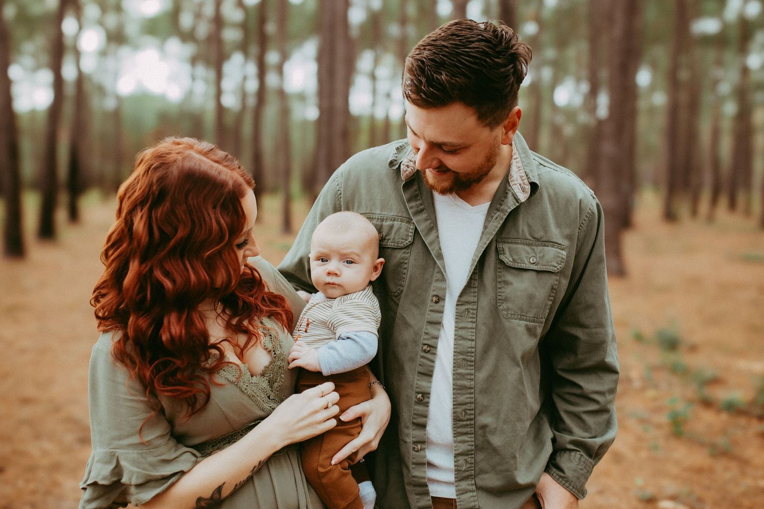 A family portrait session in a peaceful pine forest during golden hour.