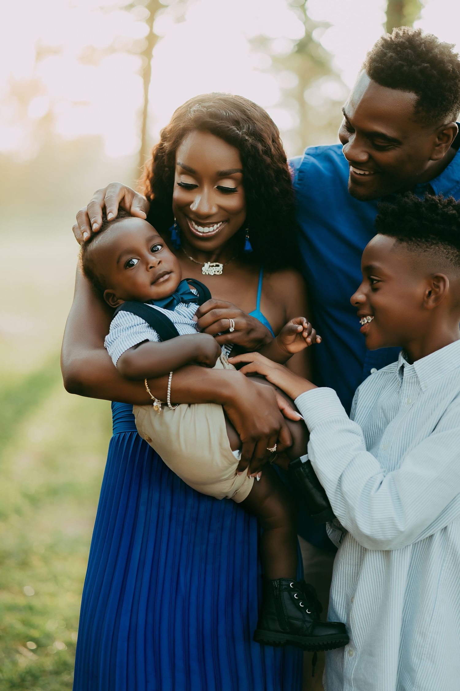 A joyful family shares loving embraces and laughter during an outdoor photo session in natural lighting.
