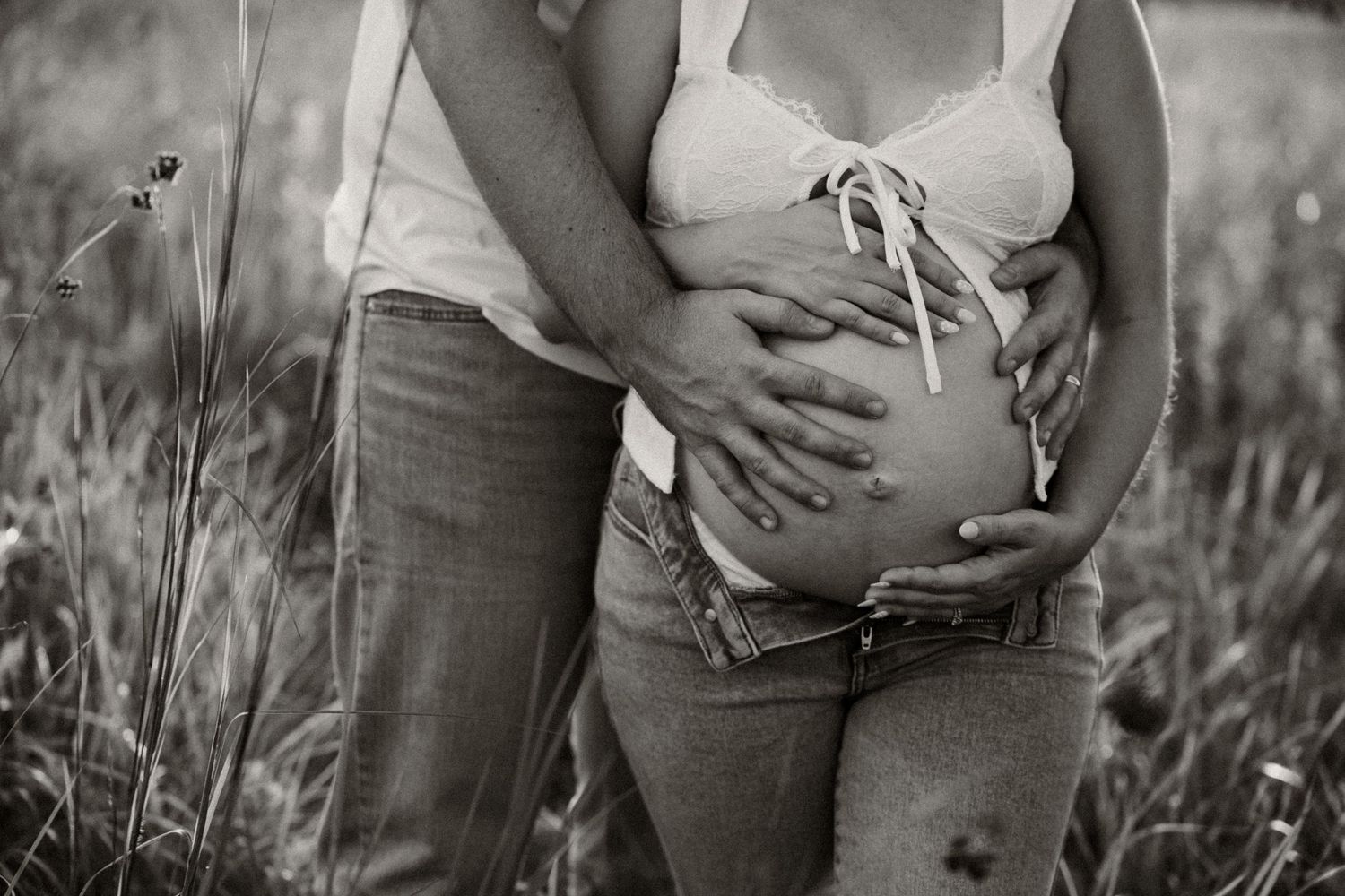 A black and white maternity photo series showing a pregnant woman's belly in a natural outdoor setting.