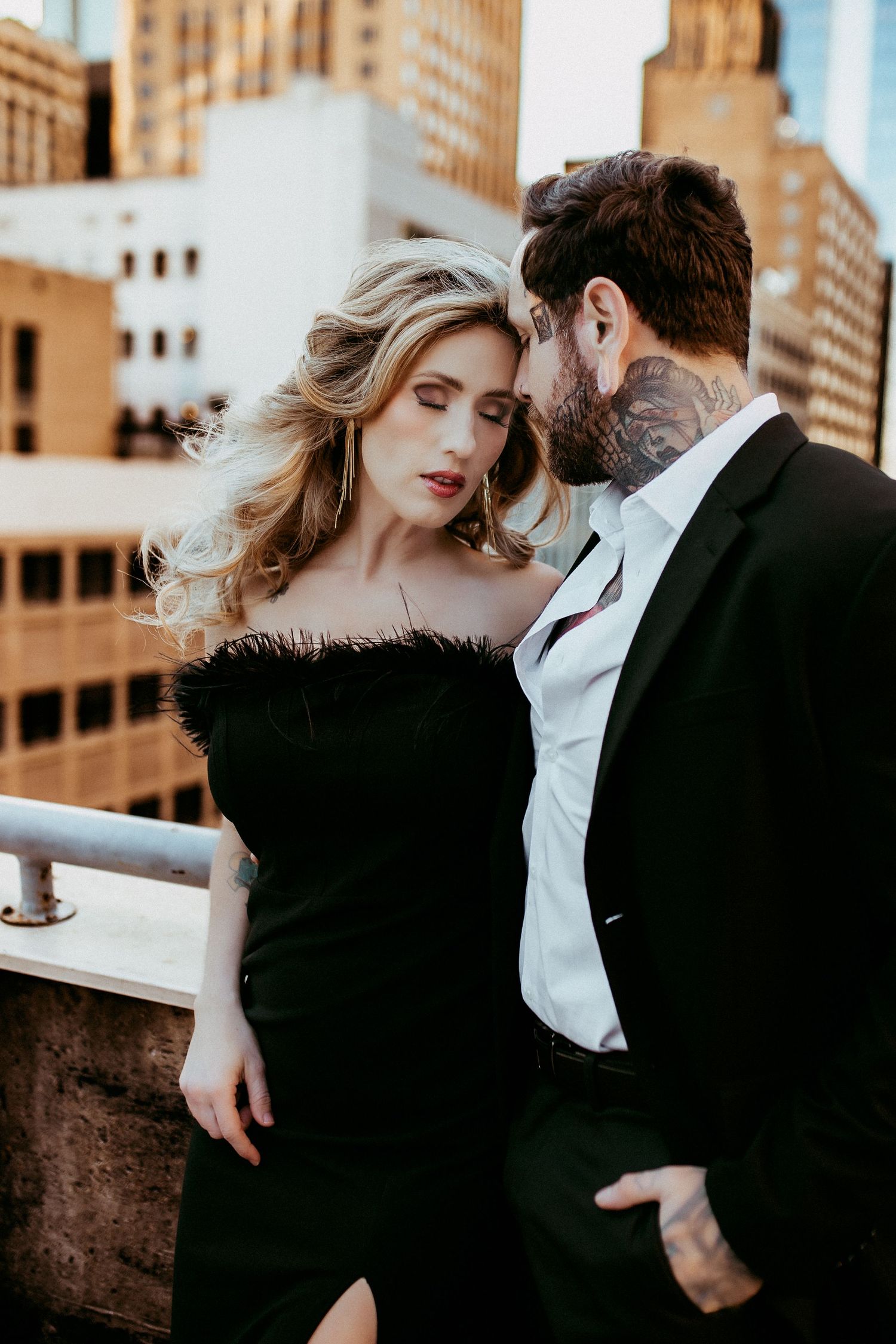 Elegant duo shares romantic moment against cityscape backdrop during golden hour.
