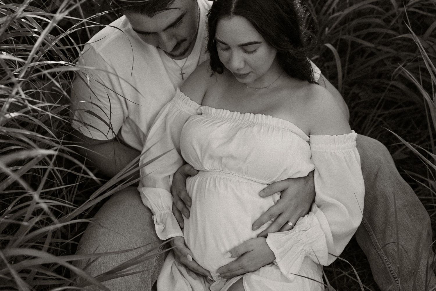 A romantic couple in white embraces tenderly in a black and white photo series.