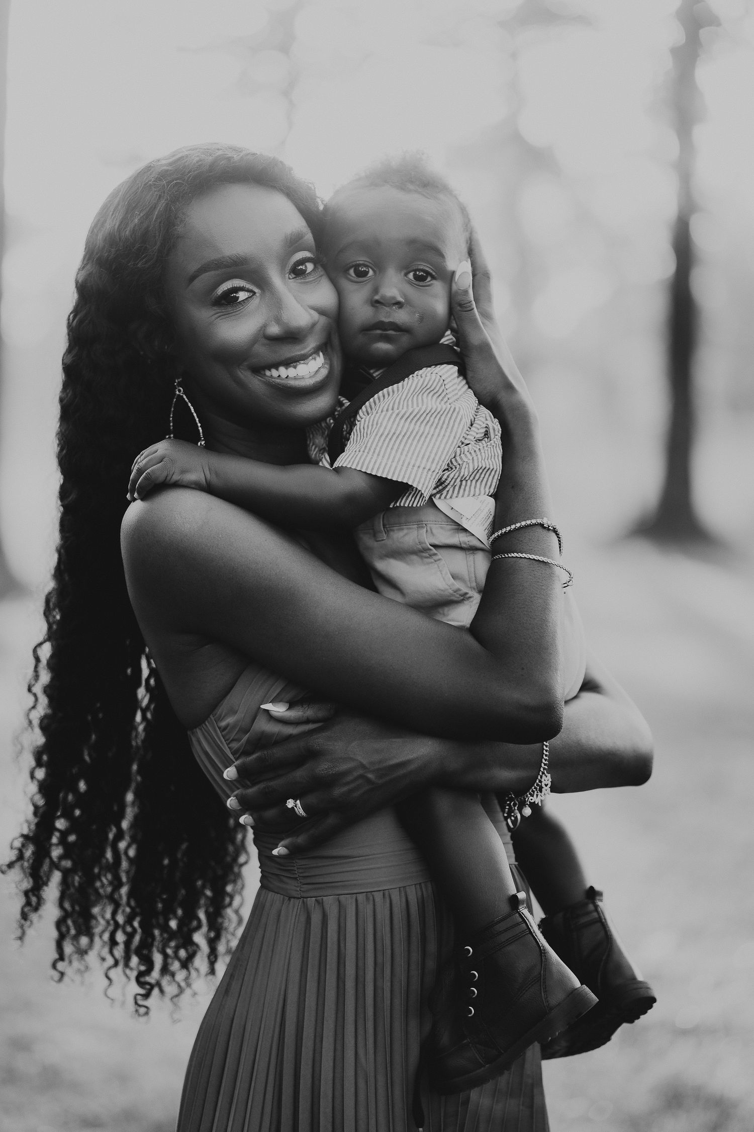 A series of joyful black and white photos showing a mother in a dress embracing her young child outdoors.