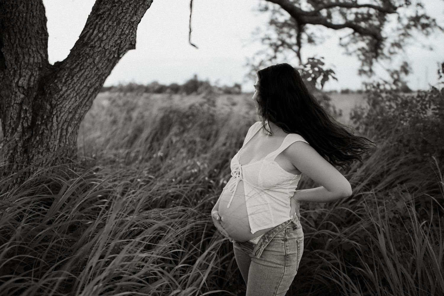 Black and white photo series showing a person in a white dress posing gracefully among tall grass in a natural outdoor setting.