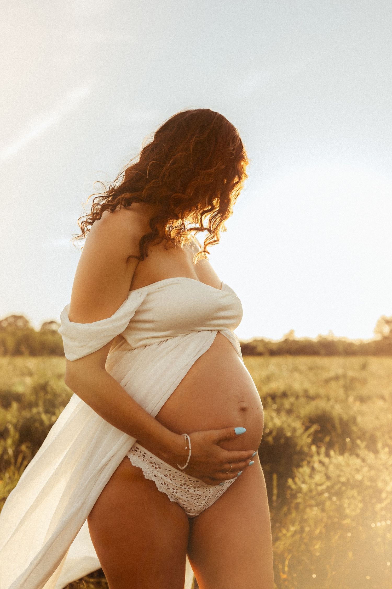 A series of pregnancy photos showing someone in a white top against a golden sunset in a field.
