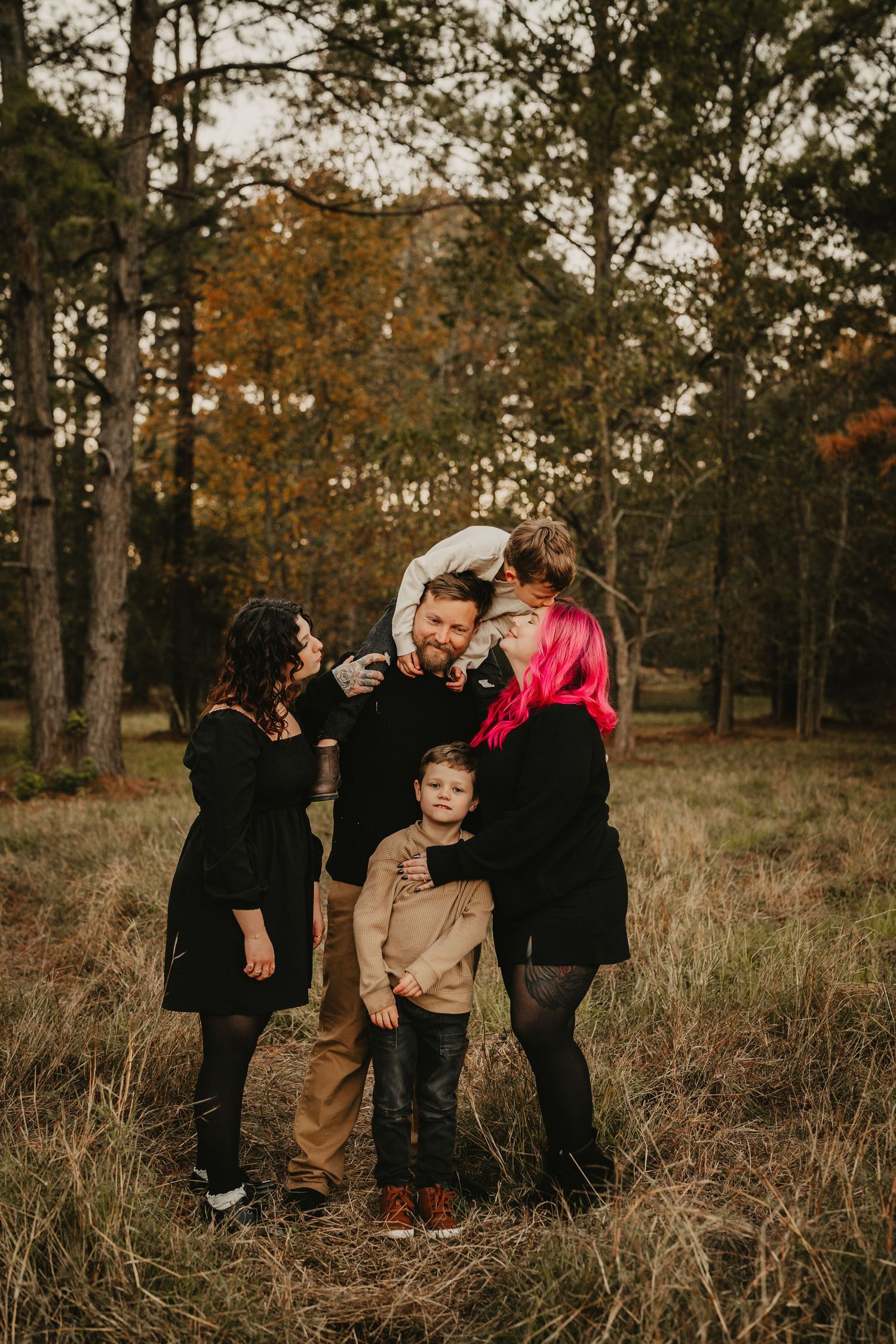 Playful family photo session with bright pink hair and laughter in an autumn field.