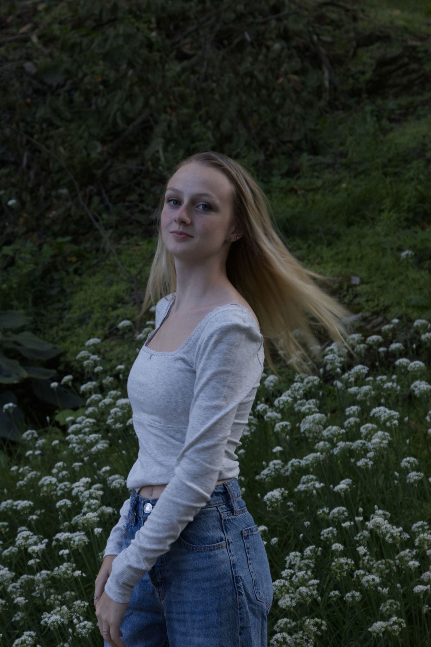A young woman curiously looks to the left, while her hair is flaring in the air.